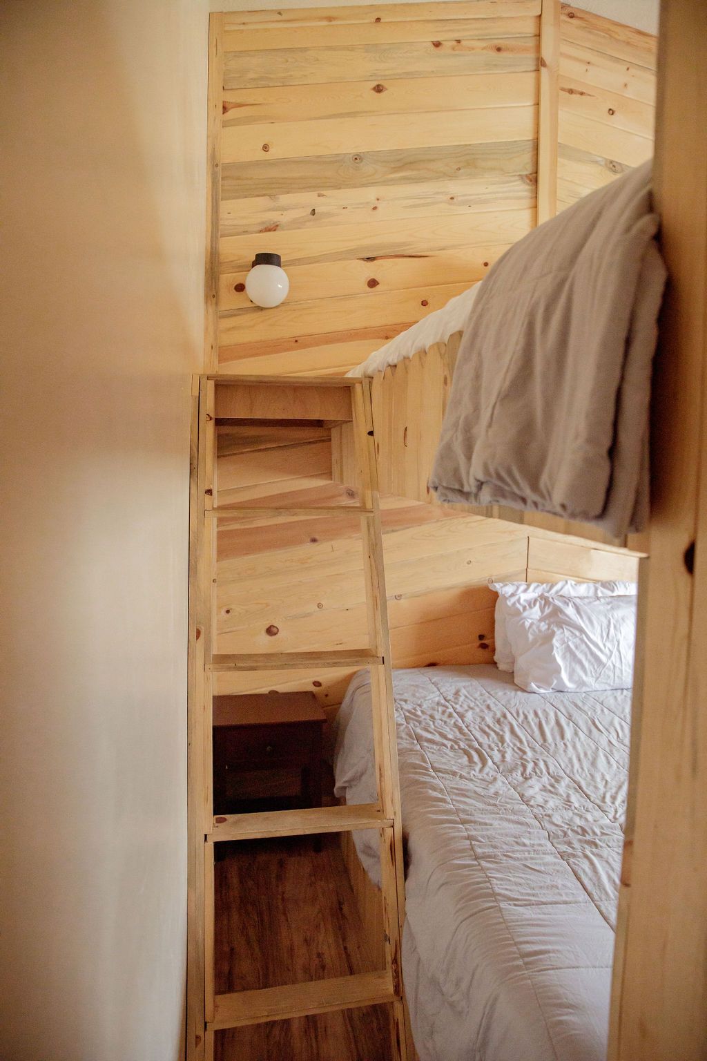 A bunk bed with a wooden ladder leading up to it.