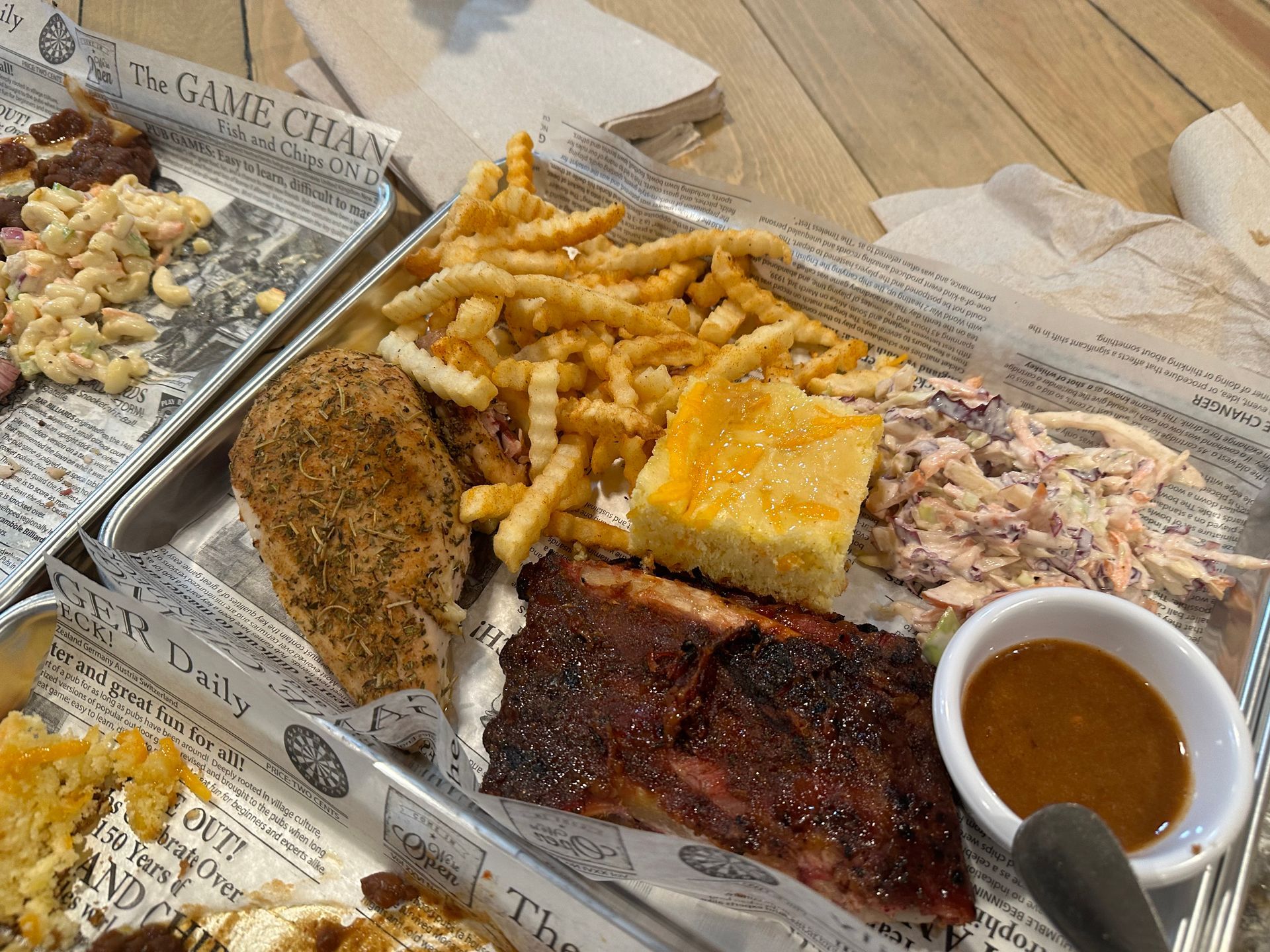 A plate of food with ribs , french fries , cornbread and coleslaw on a table.