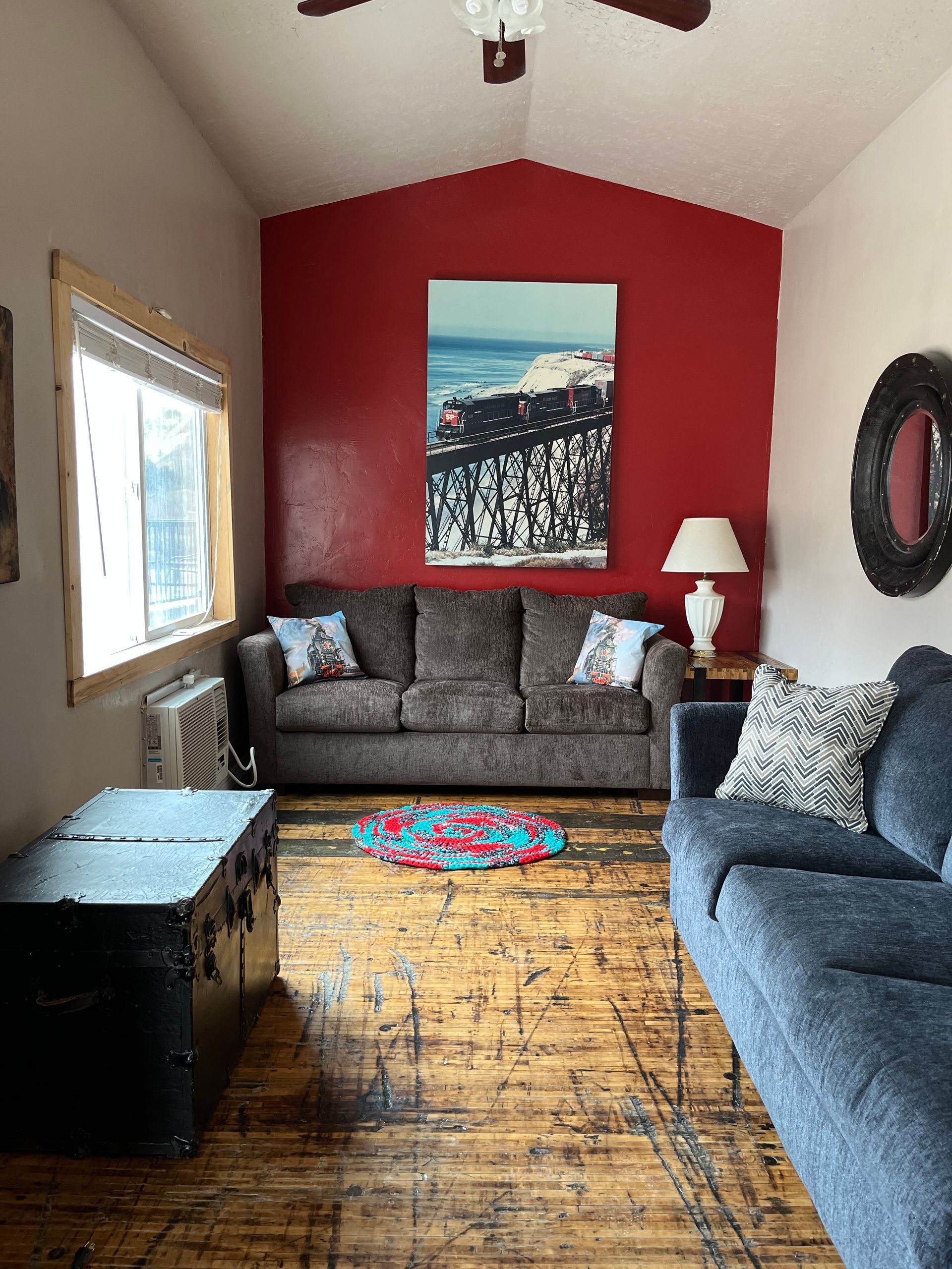 A living room with a couch , trunk and a painting on the wall.