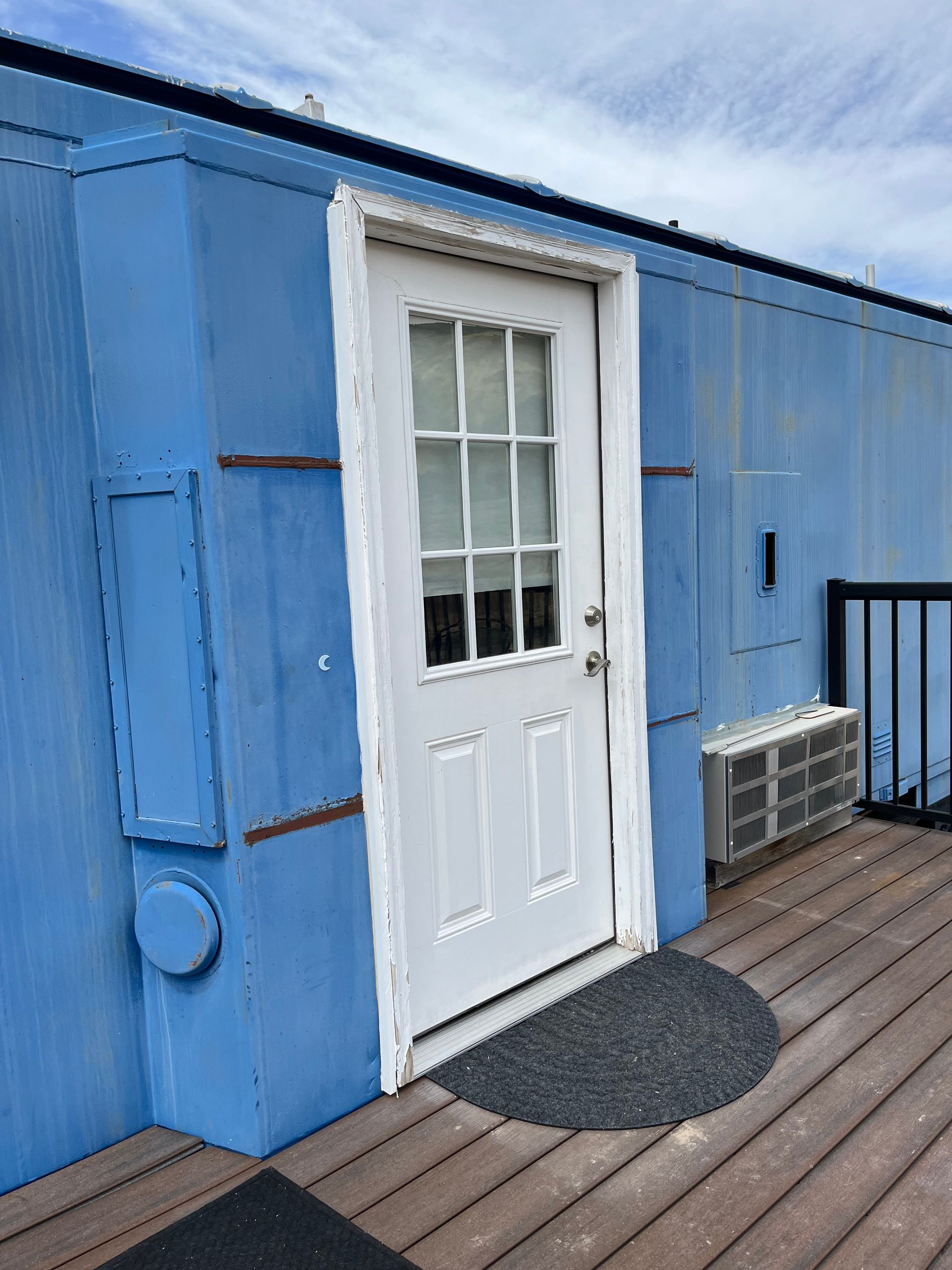 A blue building with a white door and a window.