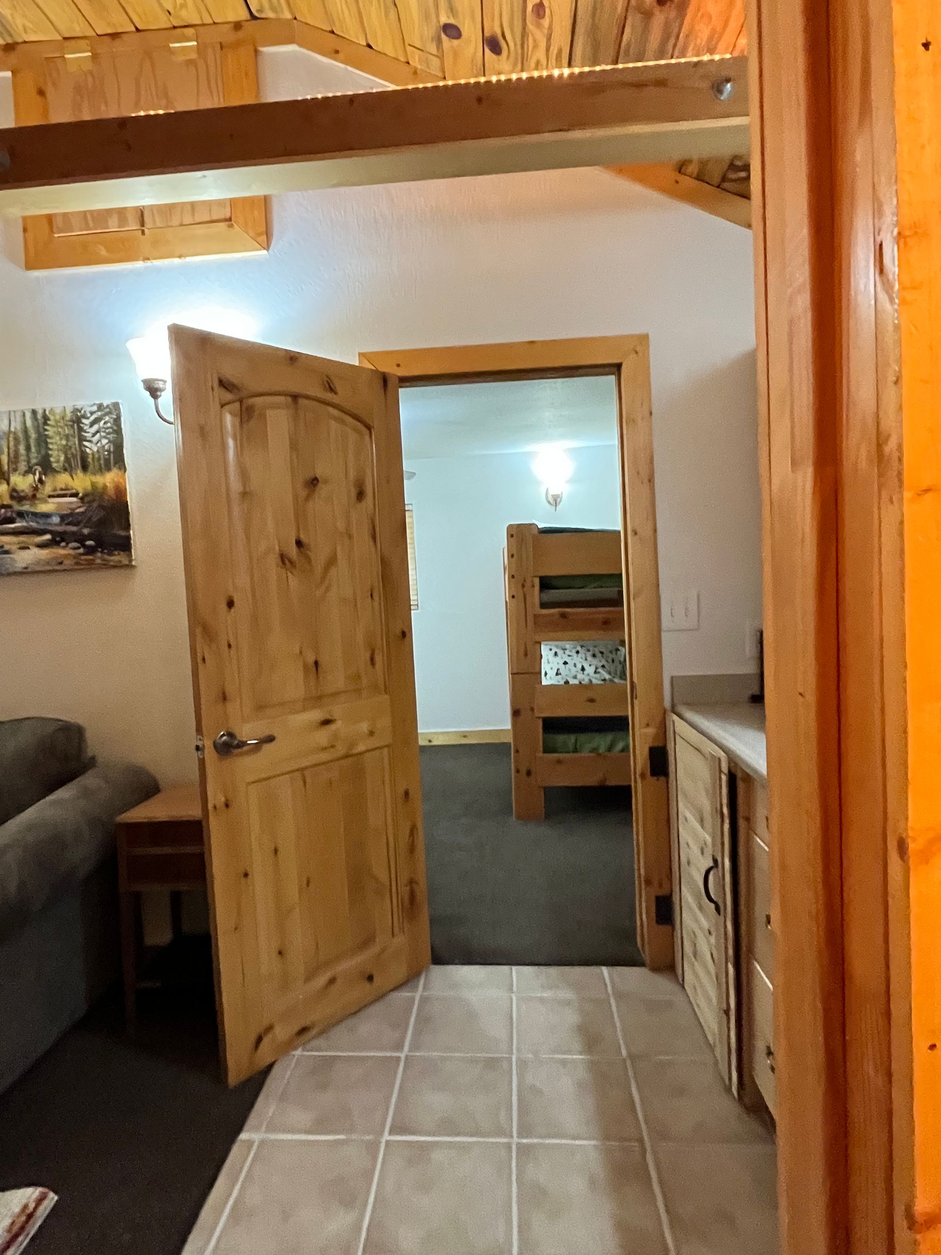 A wooden door is open to a bedroom with bunk beds.