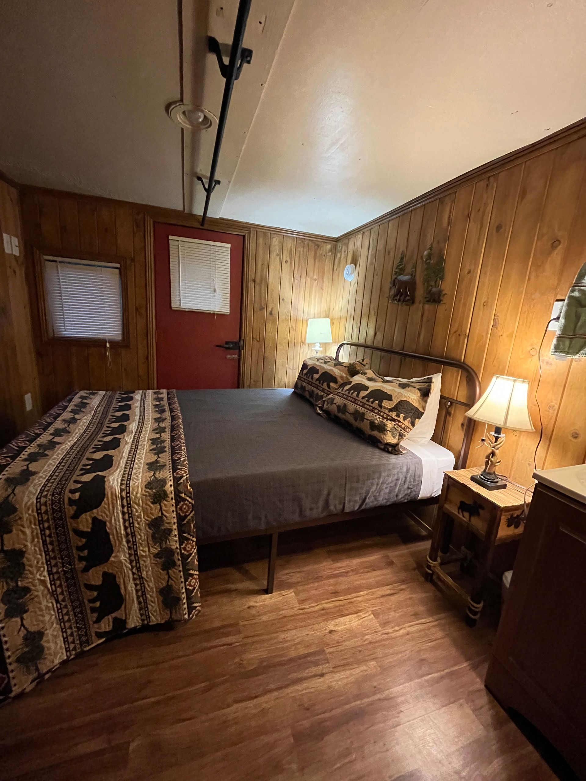 A bedroom with a bed , nightstand , lamp and dresser.