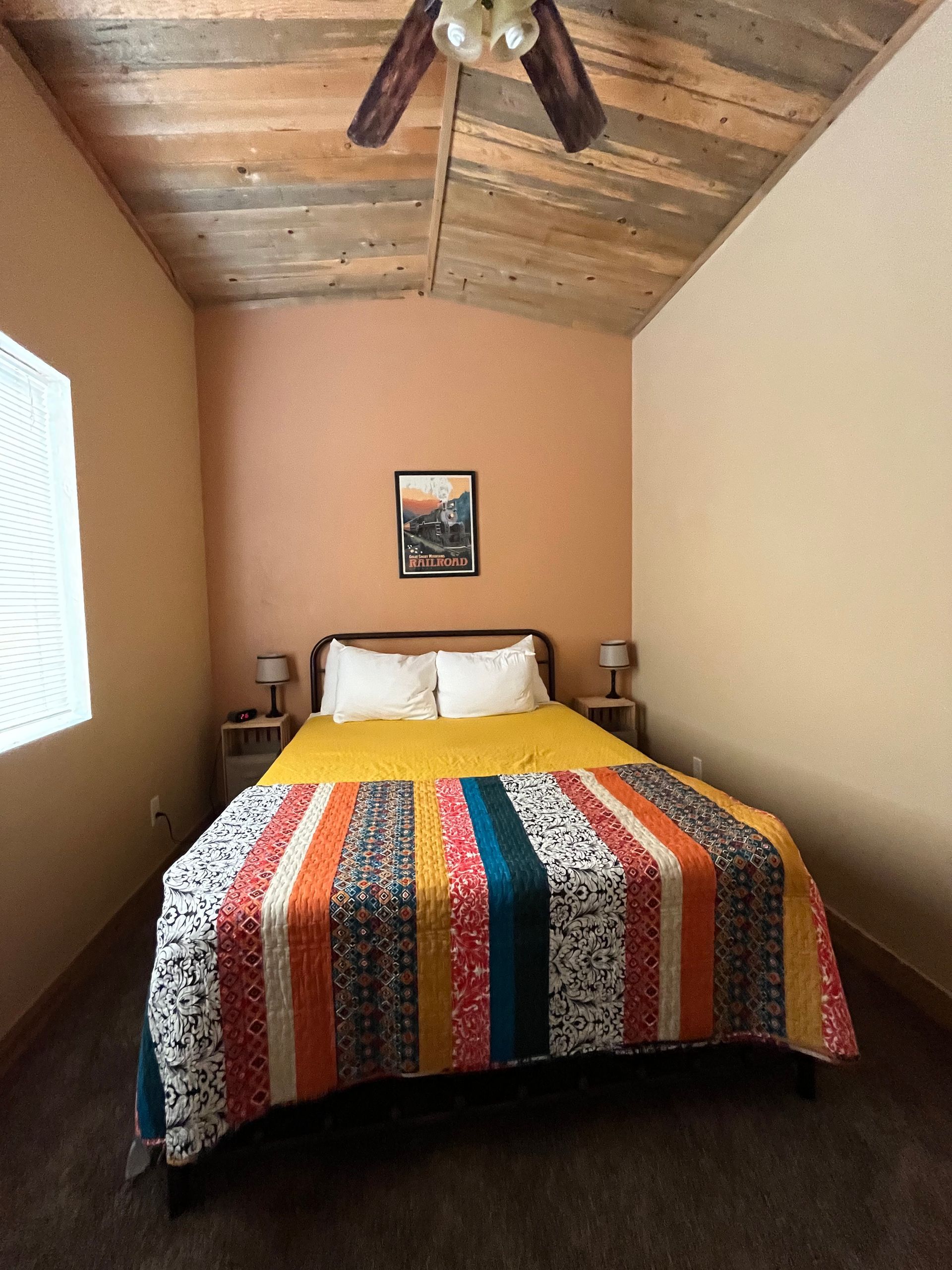 A bedroom with a bed and a ceiling fan