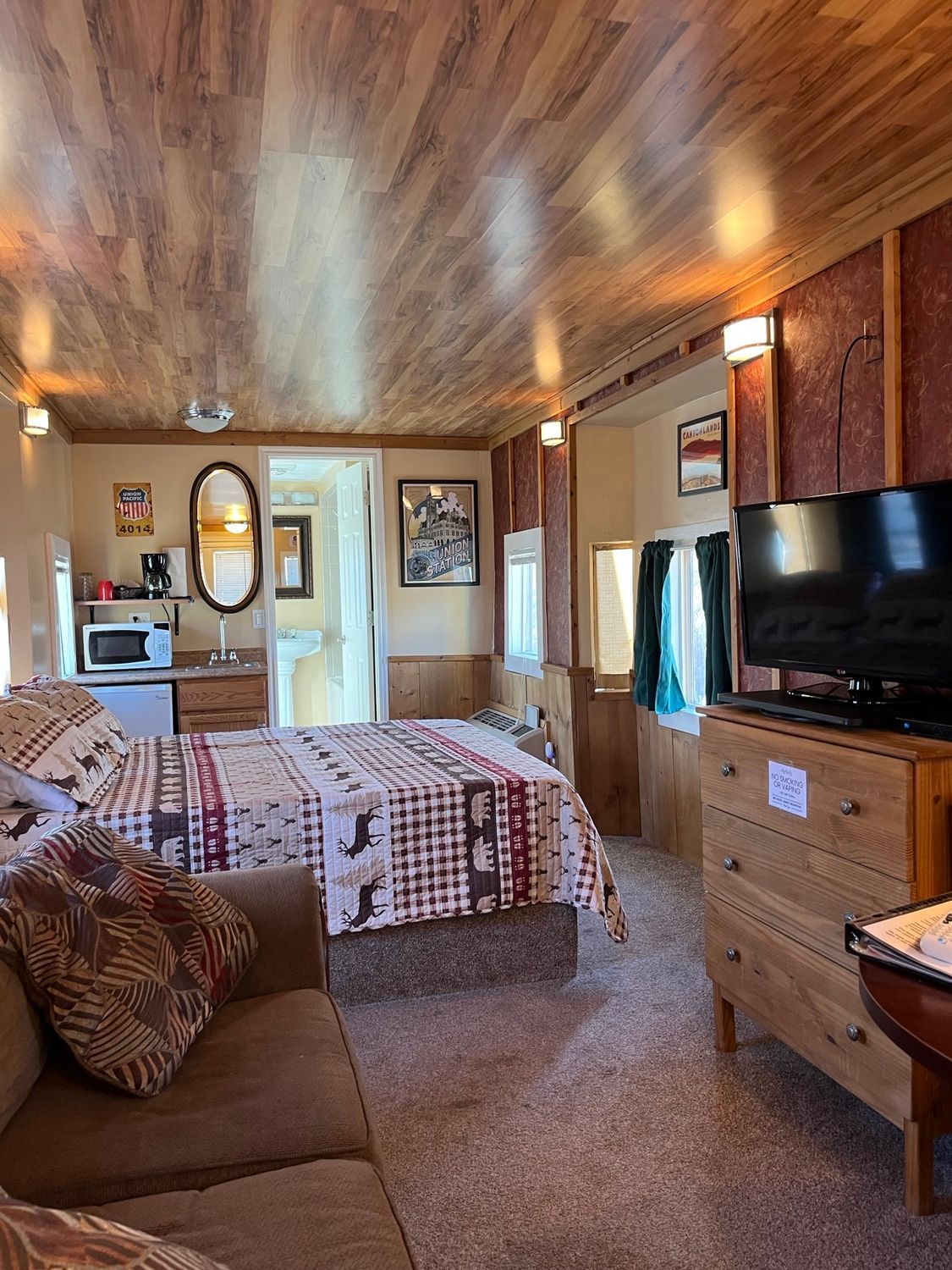 A hotel room with a bed , couch , television and dresser.