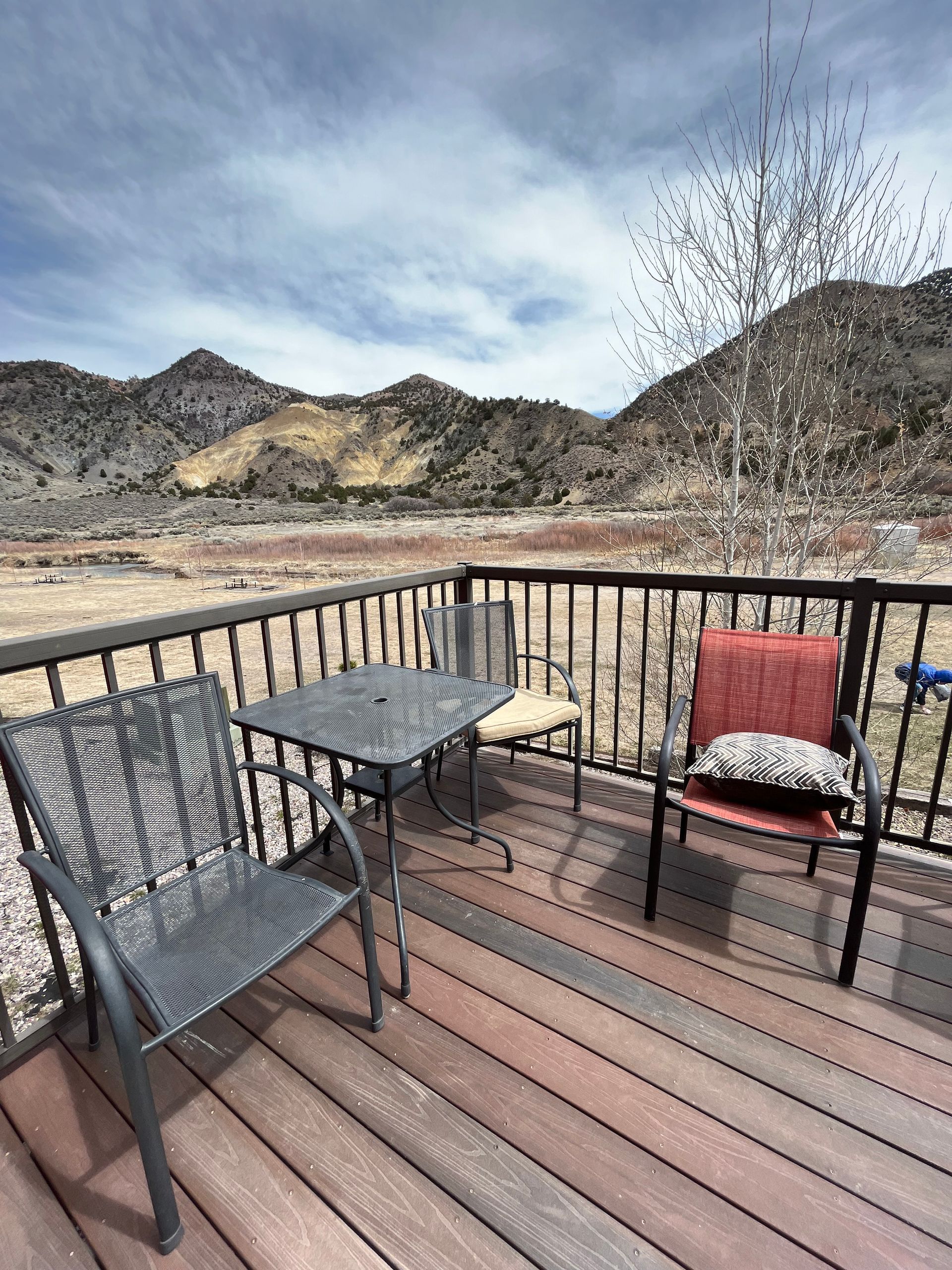 A deck with a table and chairs and mountains in the background