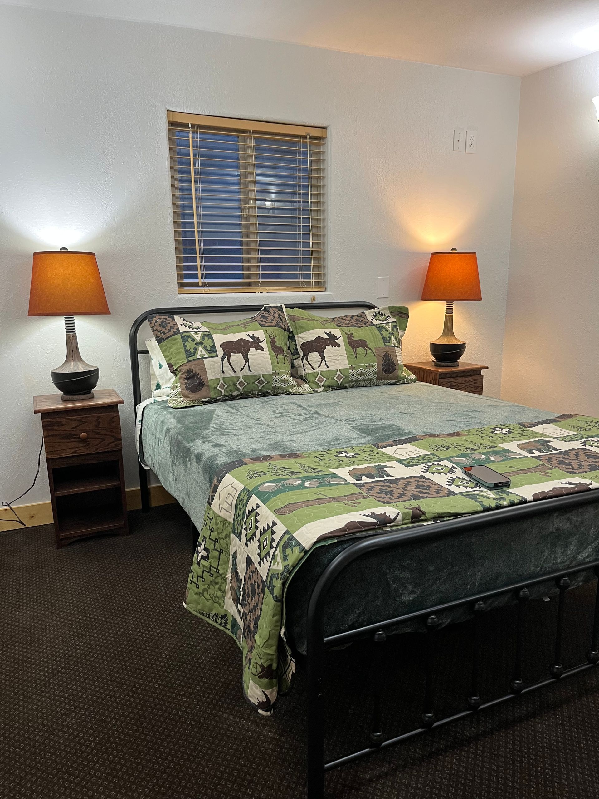 A bedroom with a bed , two lamps and a window.