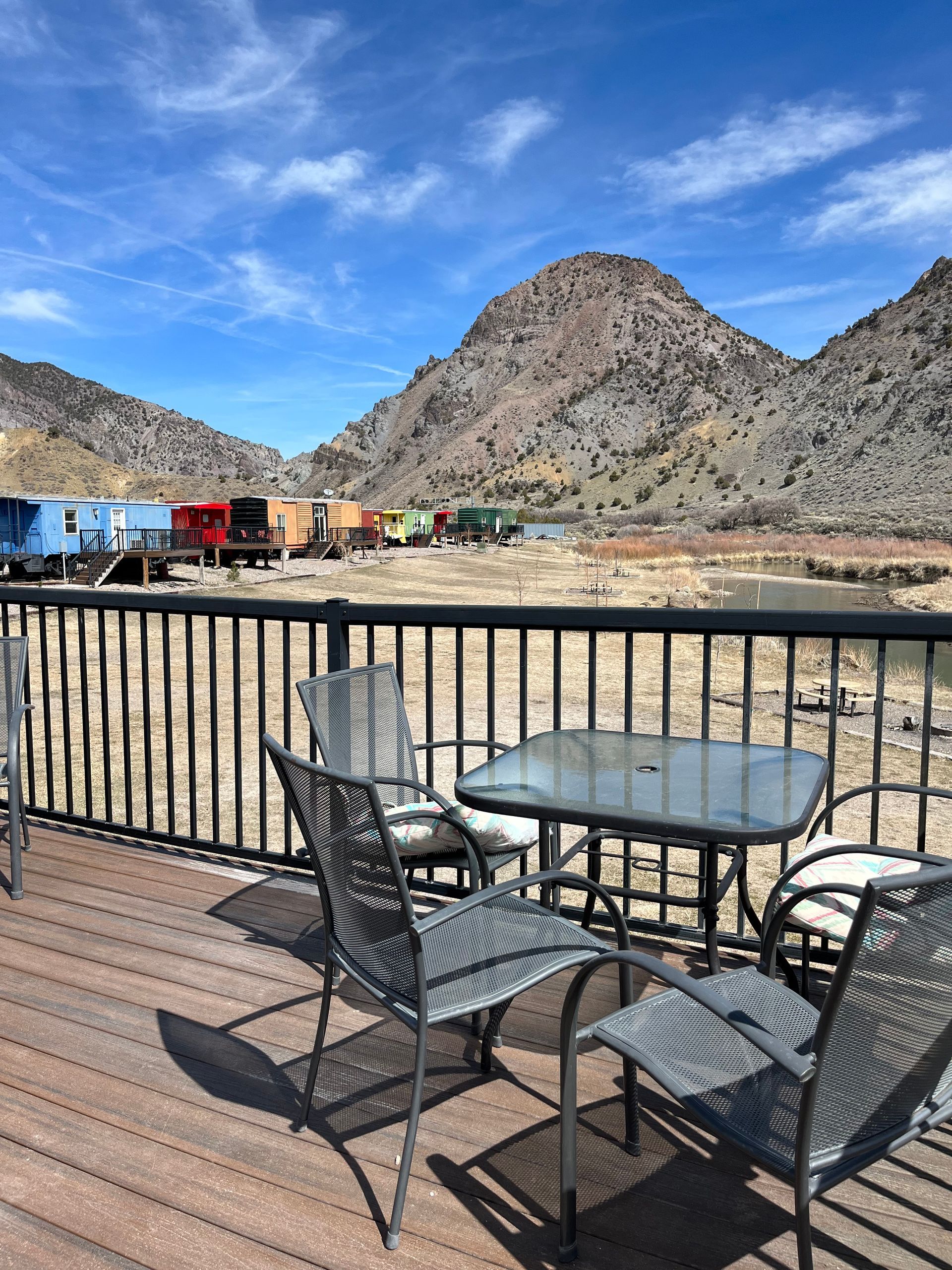 A table and chairs on a deck with mountains in the background