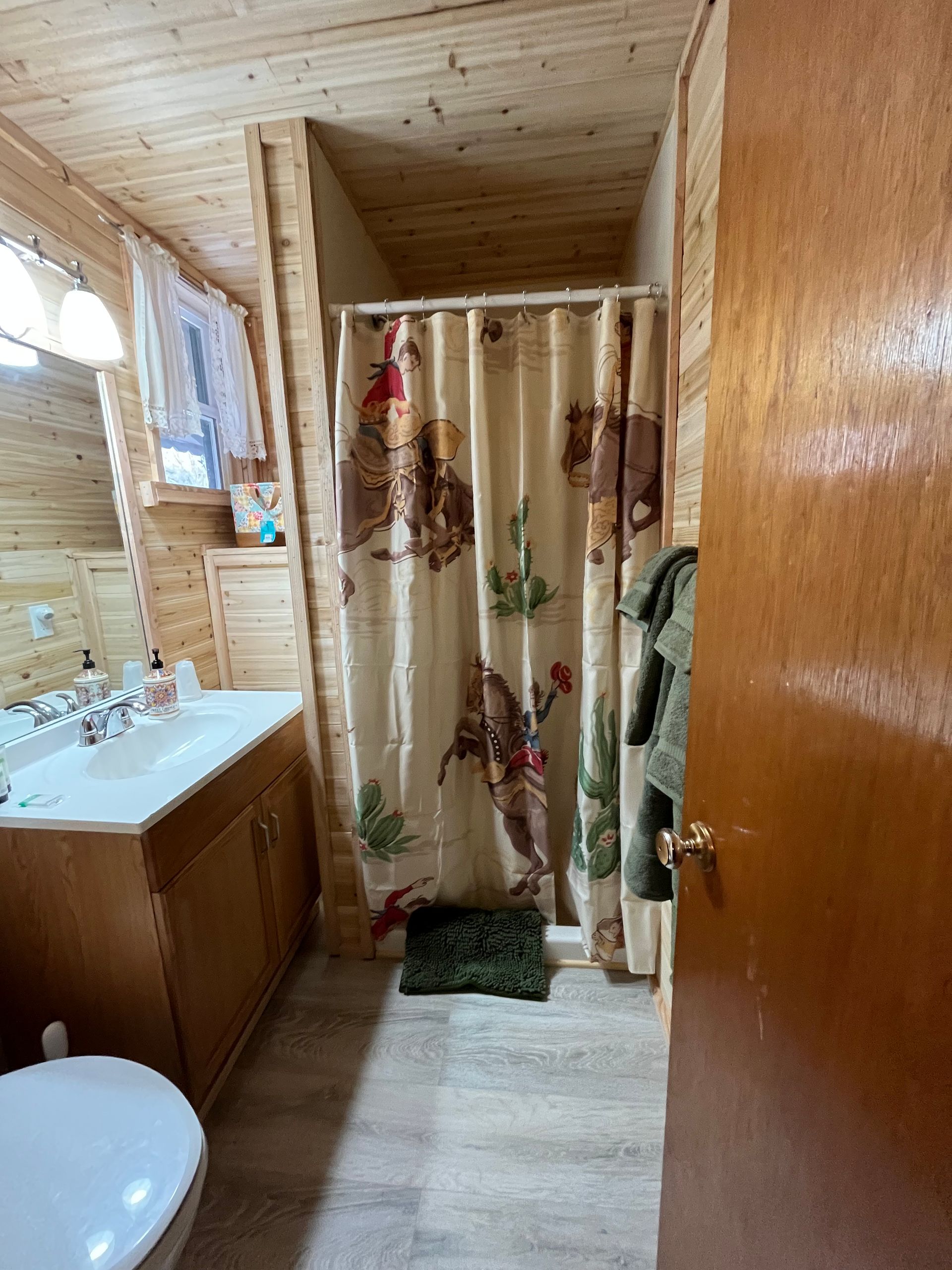 A bathroom with a shower curtain , sink , toilet and mirror.