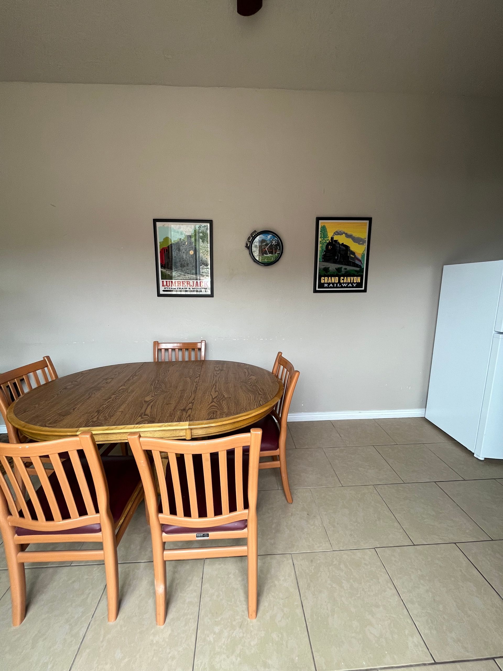 A dining room with a table and chairs and a refrigerator