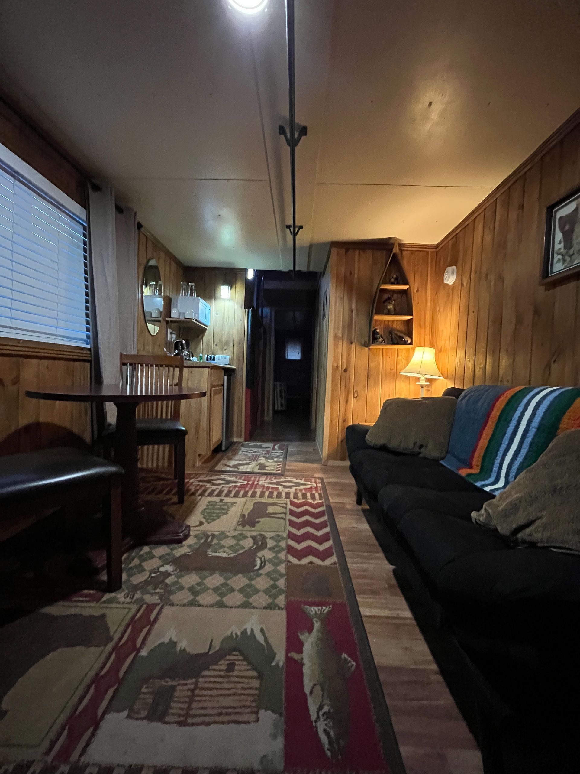 A living room with a couch , table , chairs and a rug.