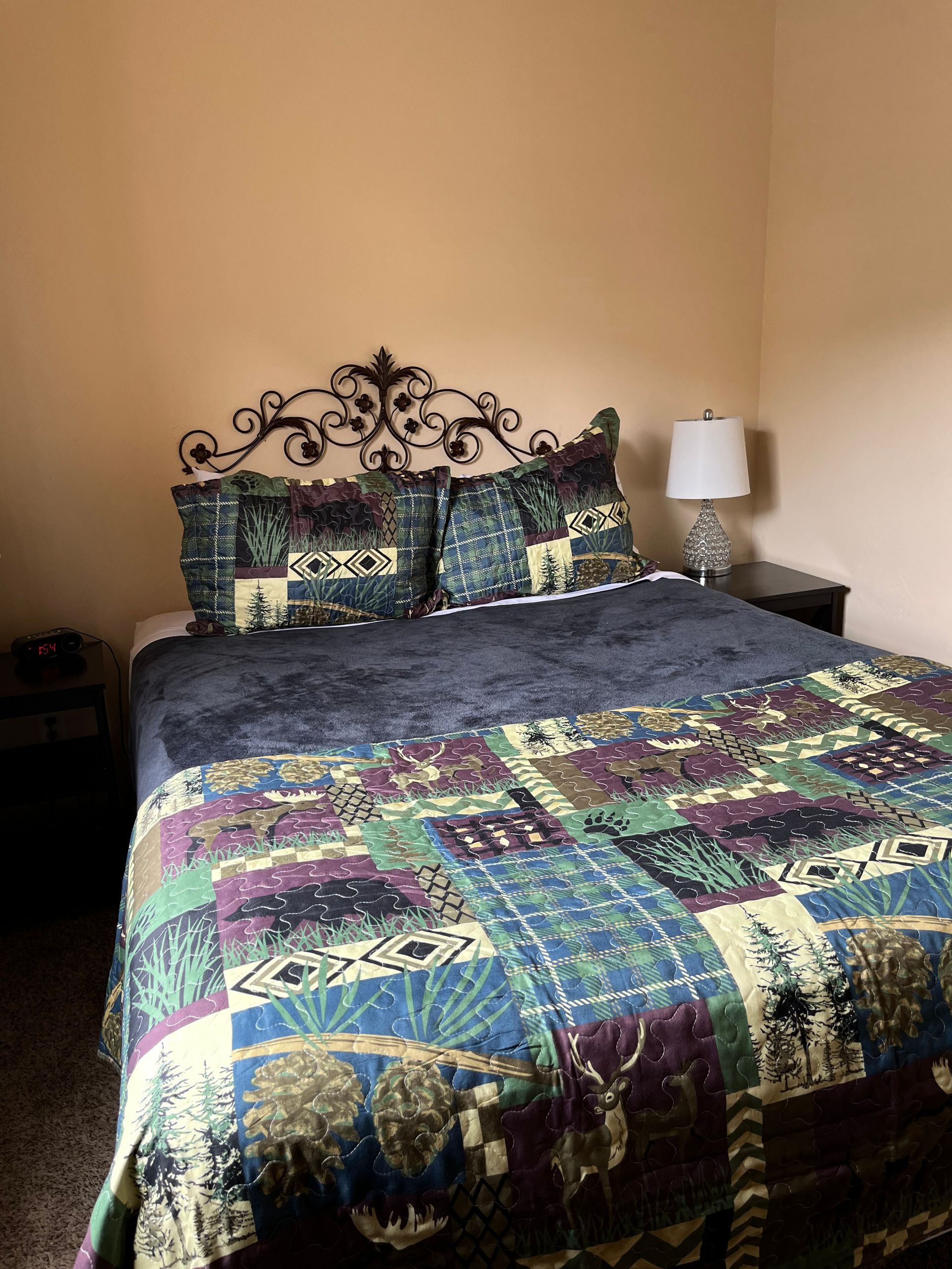 A bed with a quilt and pillows in a bedroom with a lamp.