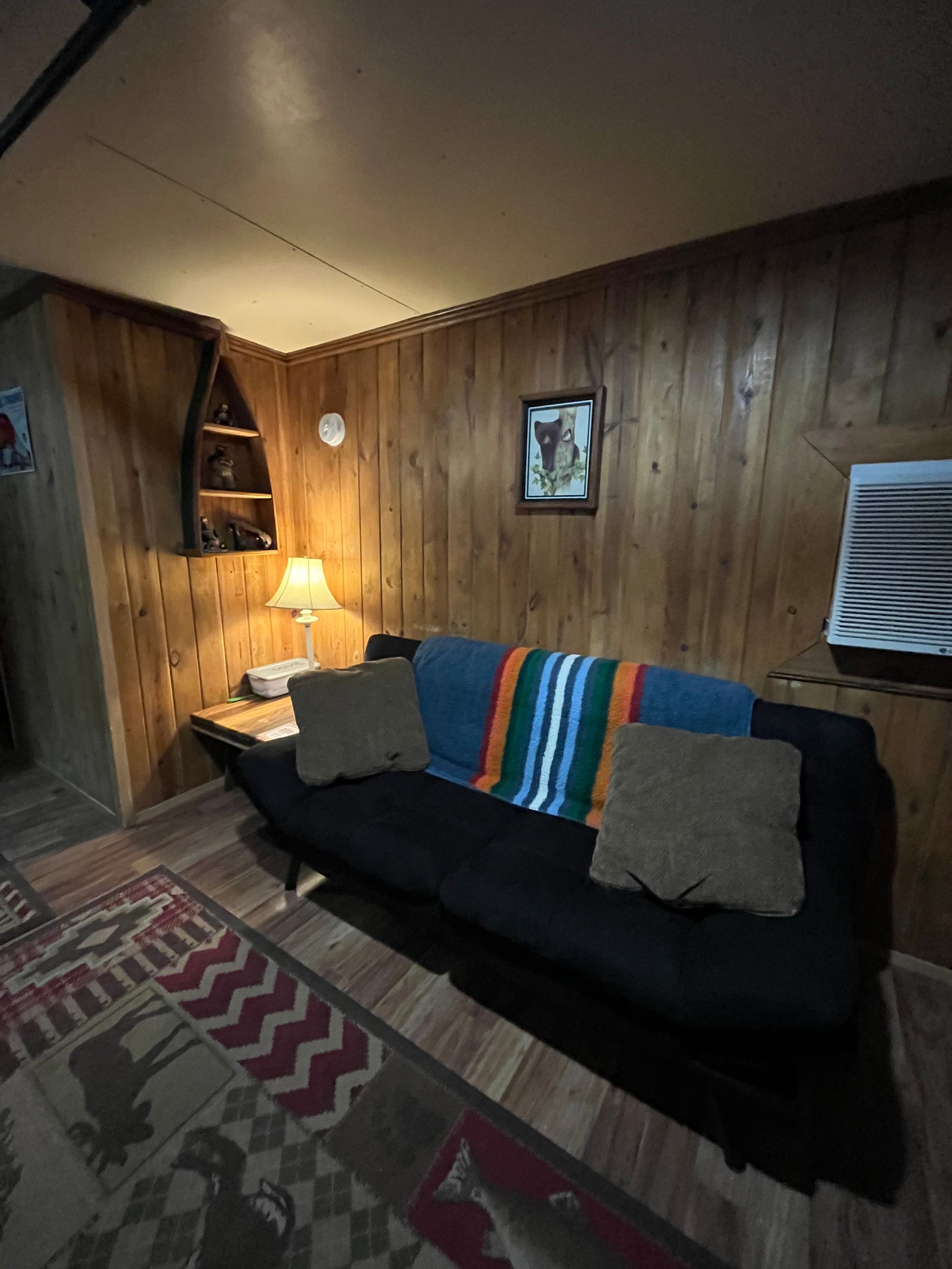 A living room with wood paneling and a black couch