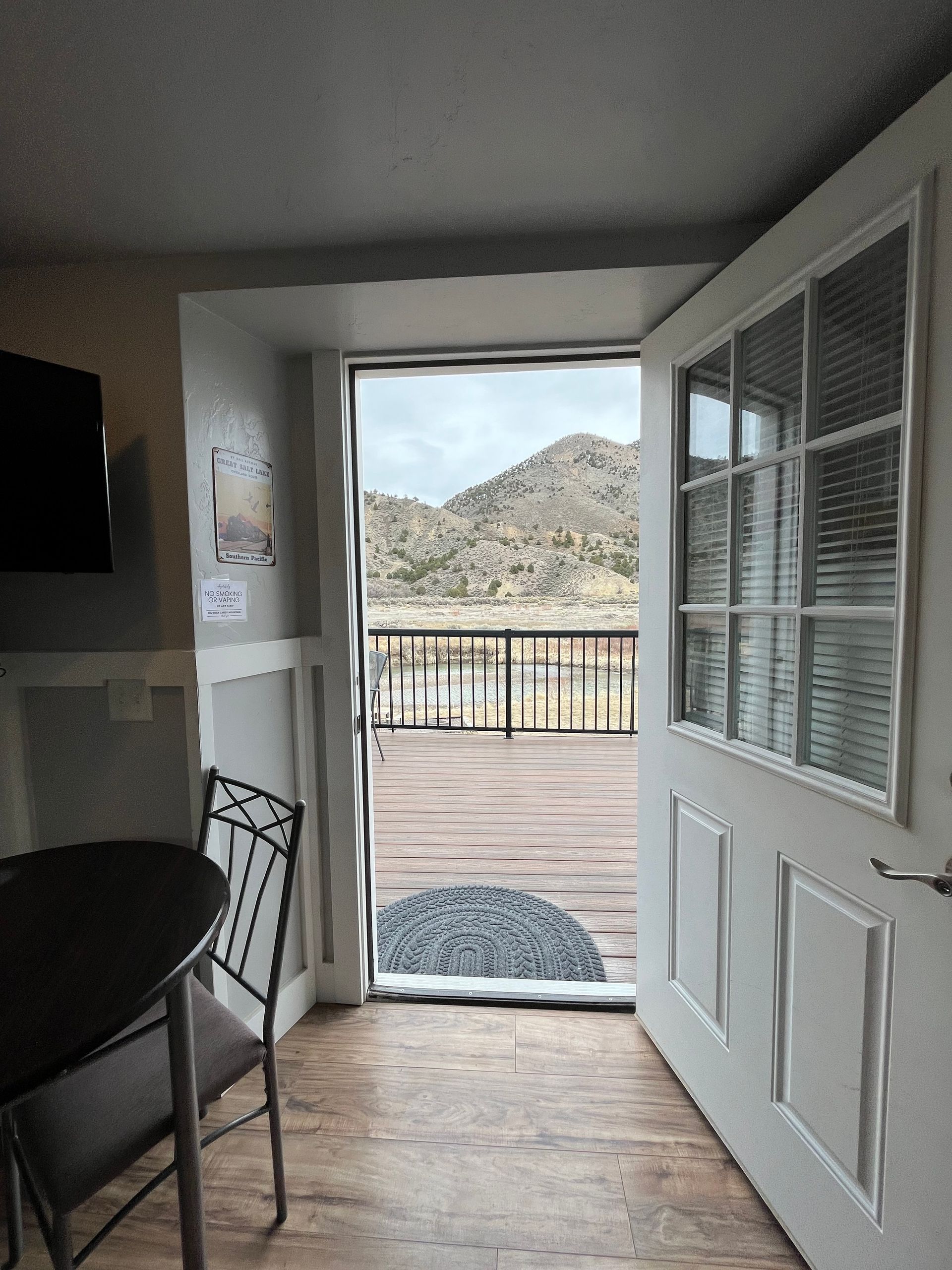 A room with a table and chairs and a door that opens to a balcony.