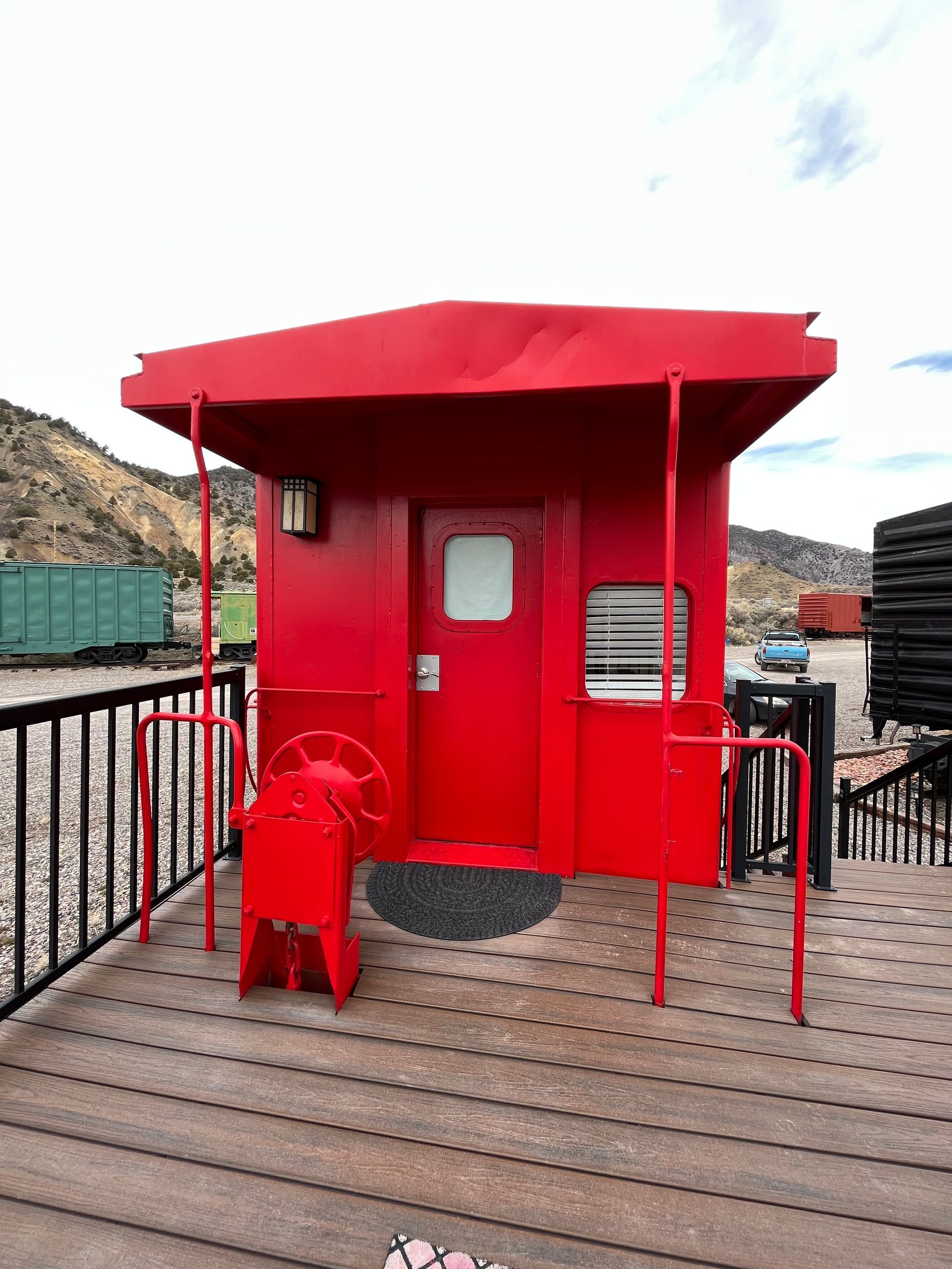 A red building with a red roof is sitting on a wooden deck.