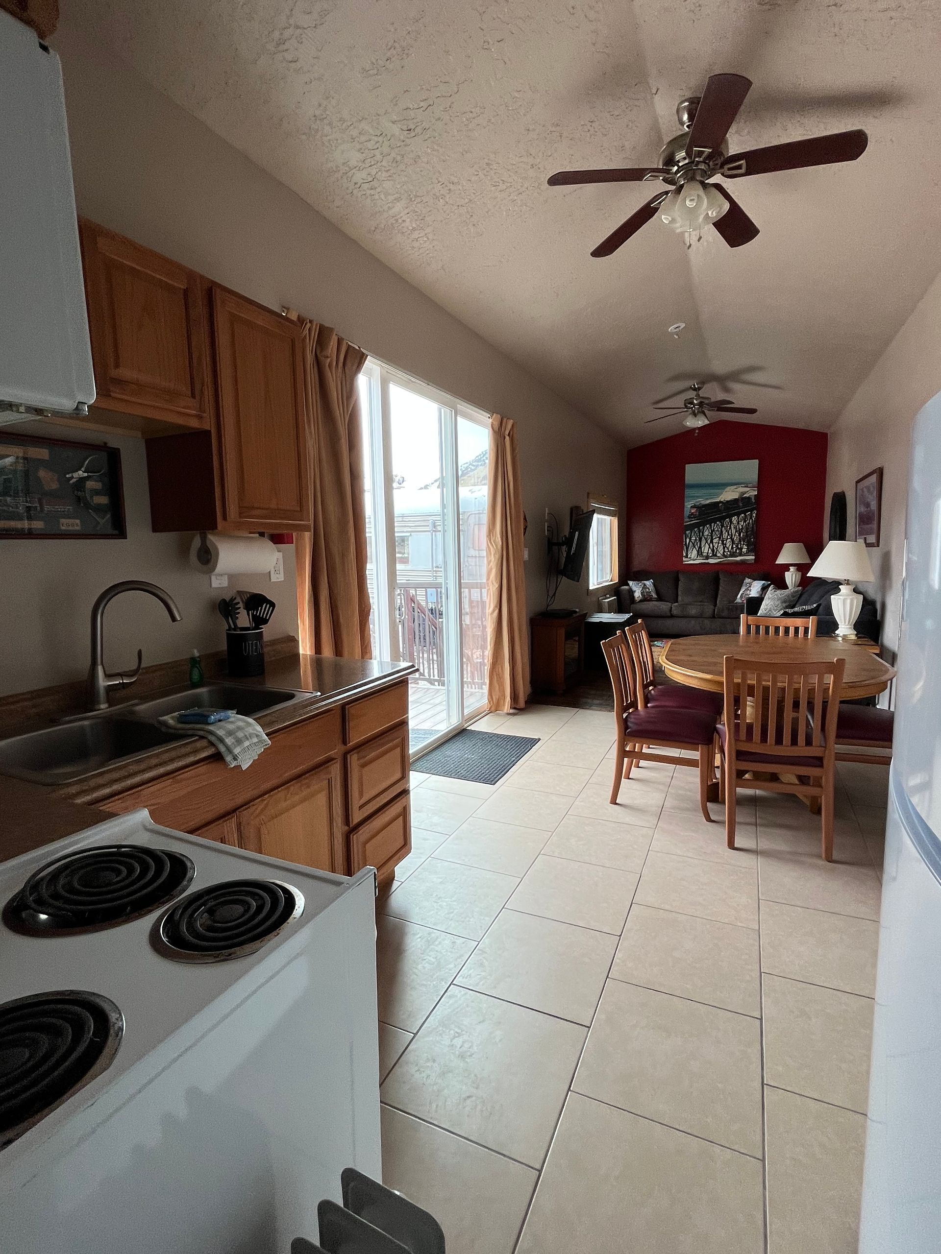 A kitchen with a stove a sink and a ceiling fan