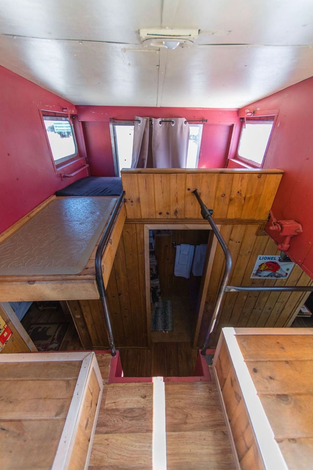 A wooden staircase leading up to a bedroom in a small house.