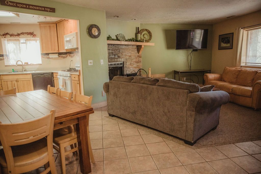 A living room with a couch , chairs , a table and a television.