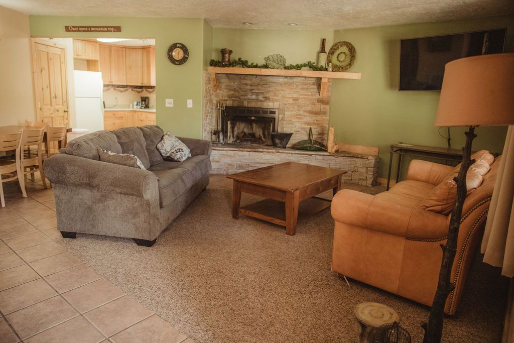 A living room with a couch , chair , coffee table and fireplace.