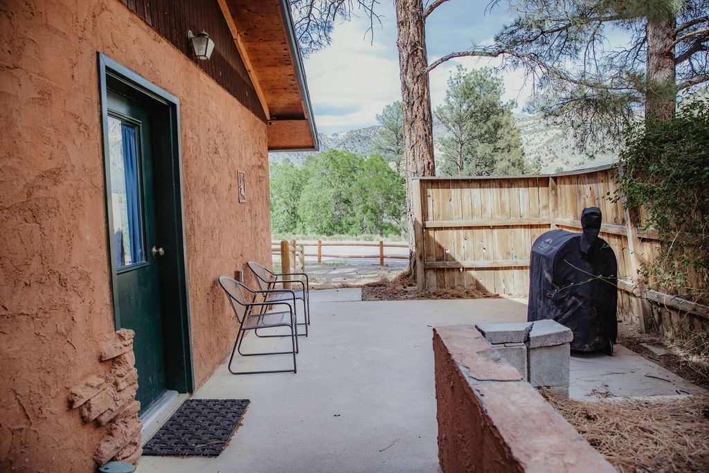 A house with a patio and a grill in front of it.