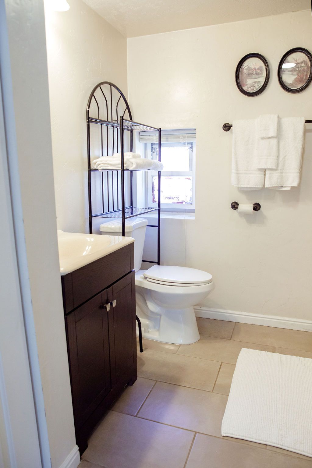 A bathroom with a toilet , sink , and towel rack.