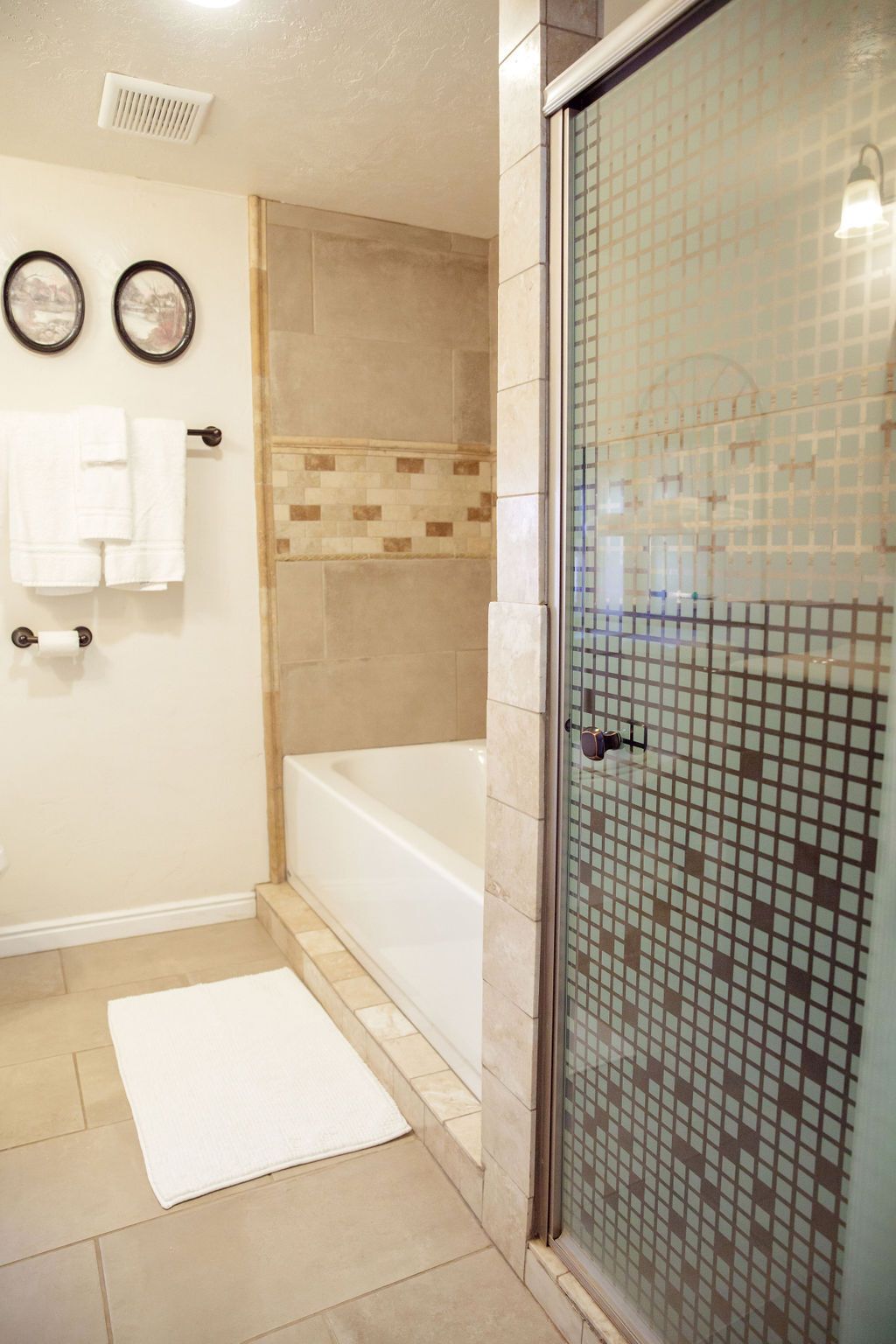 A bathroom with a bathtub , shower , and sliding glass door.