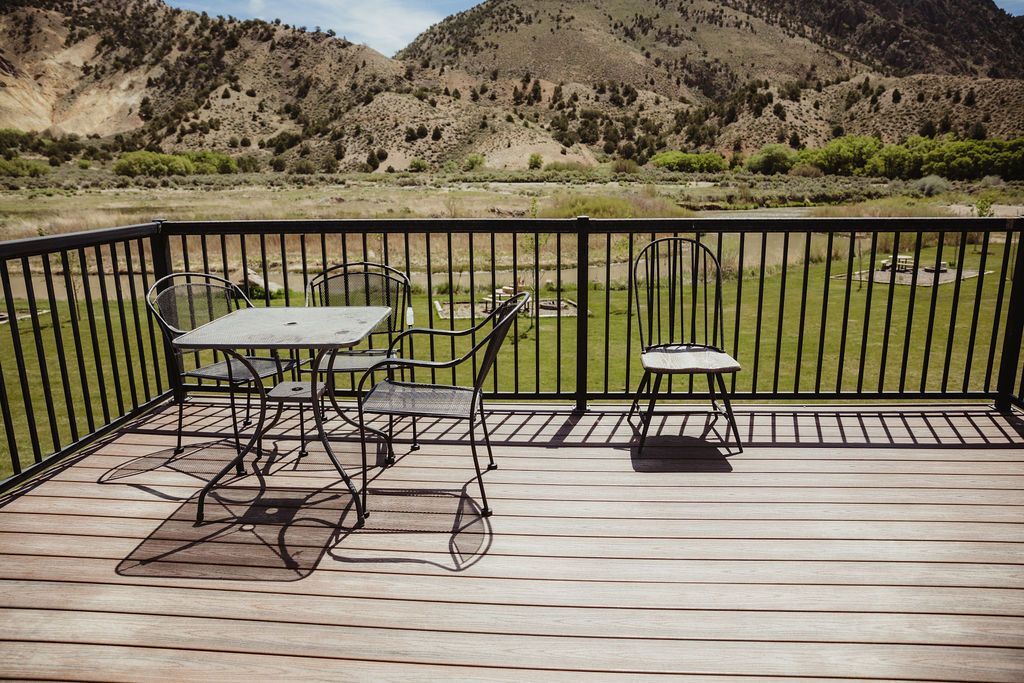 A deck with a table and chairs and mountains in the background