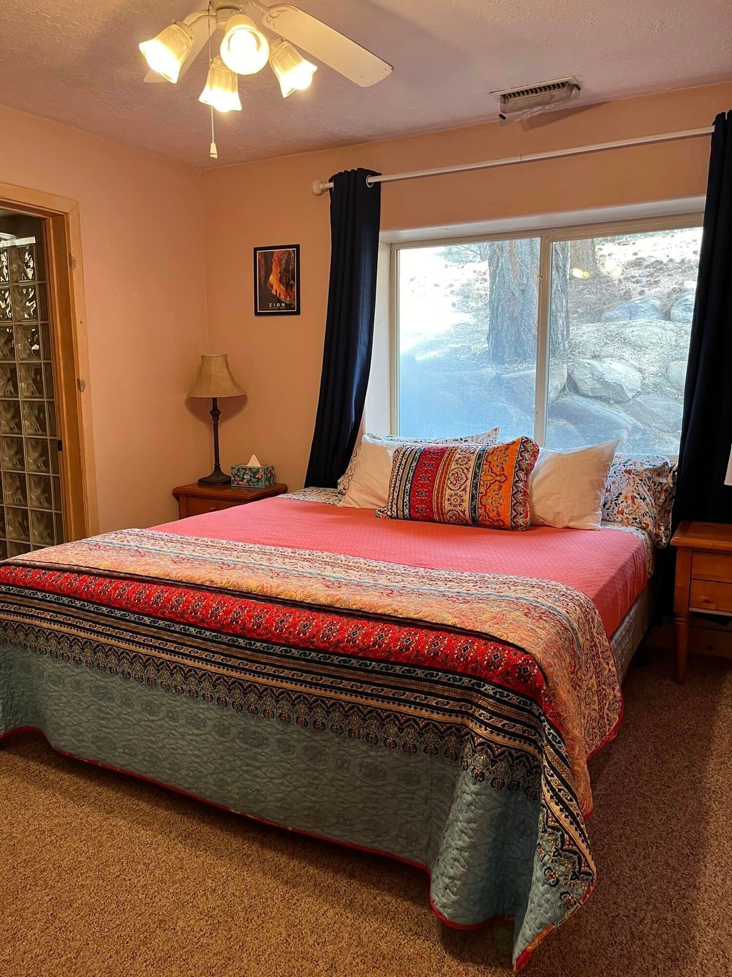 A bedroom with a bed , nightstand , ceiling fan and window.