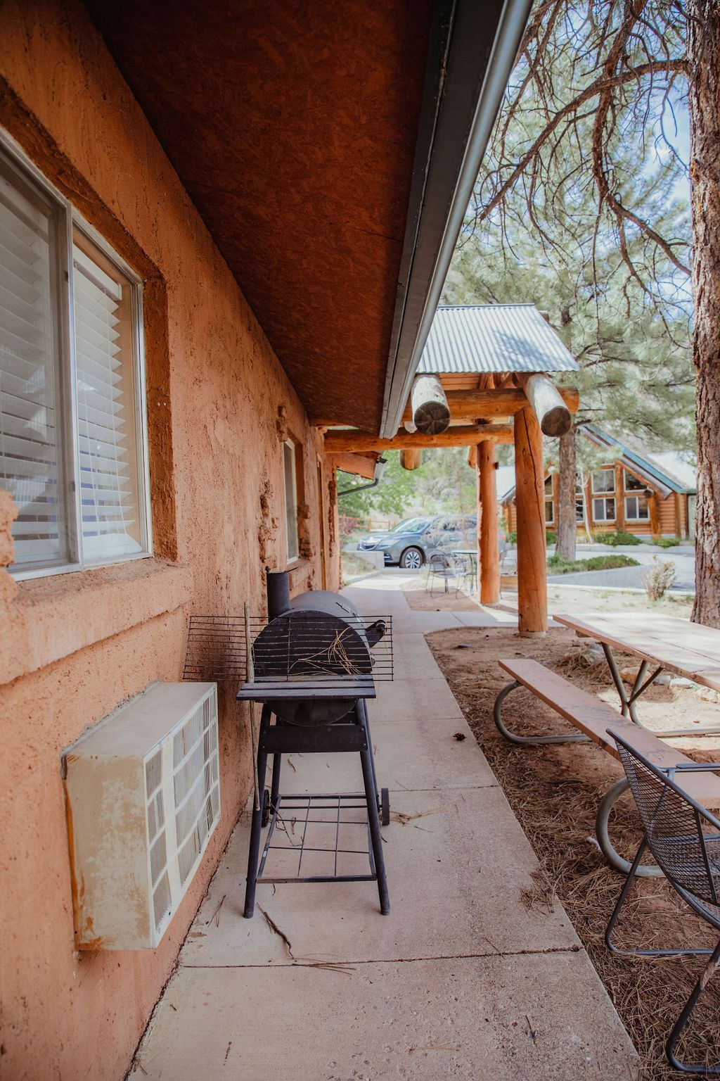 A grill is sitting on the side of a building next to a picnic table.