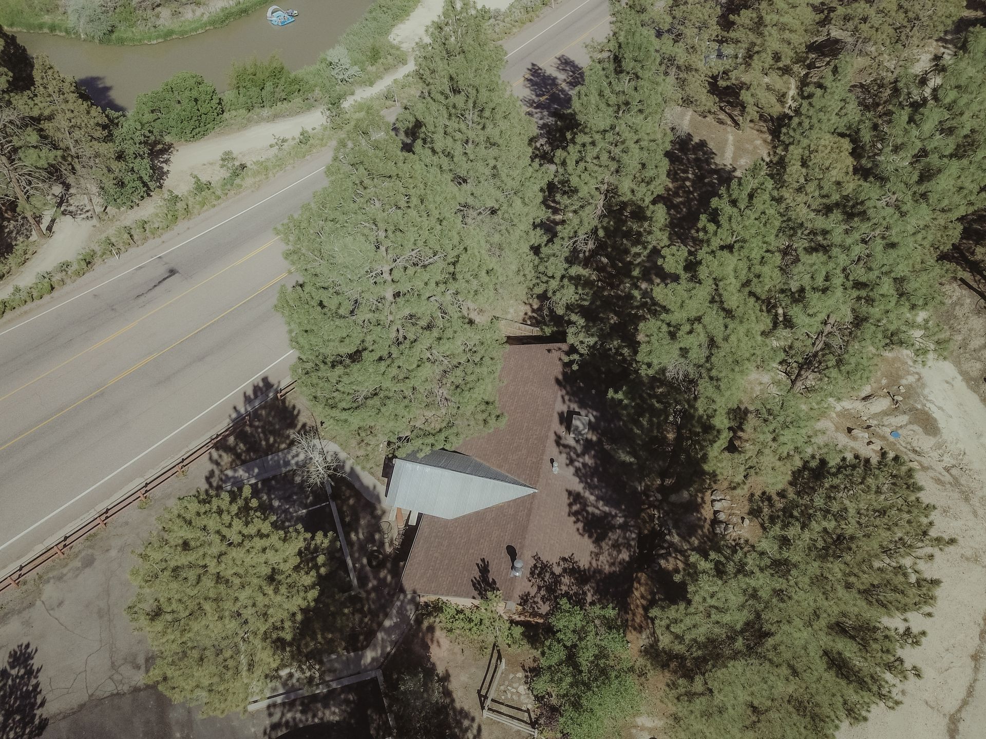 An aerial view of a house surrounded by trees and a road