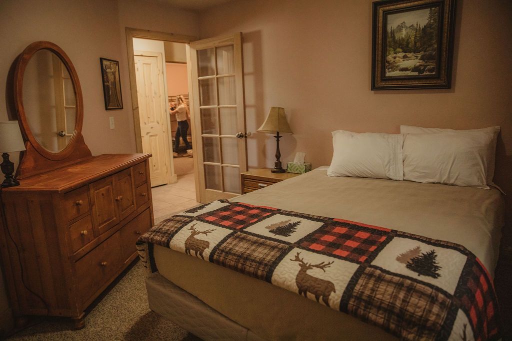 A bedroom with a bed , dresser and mirror.