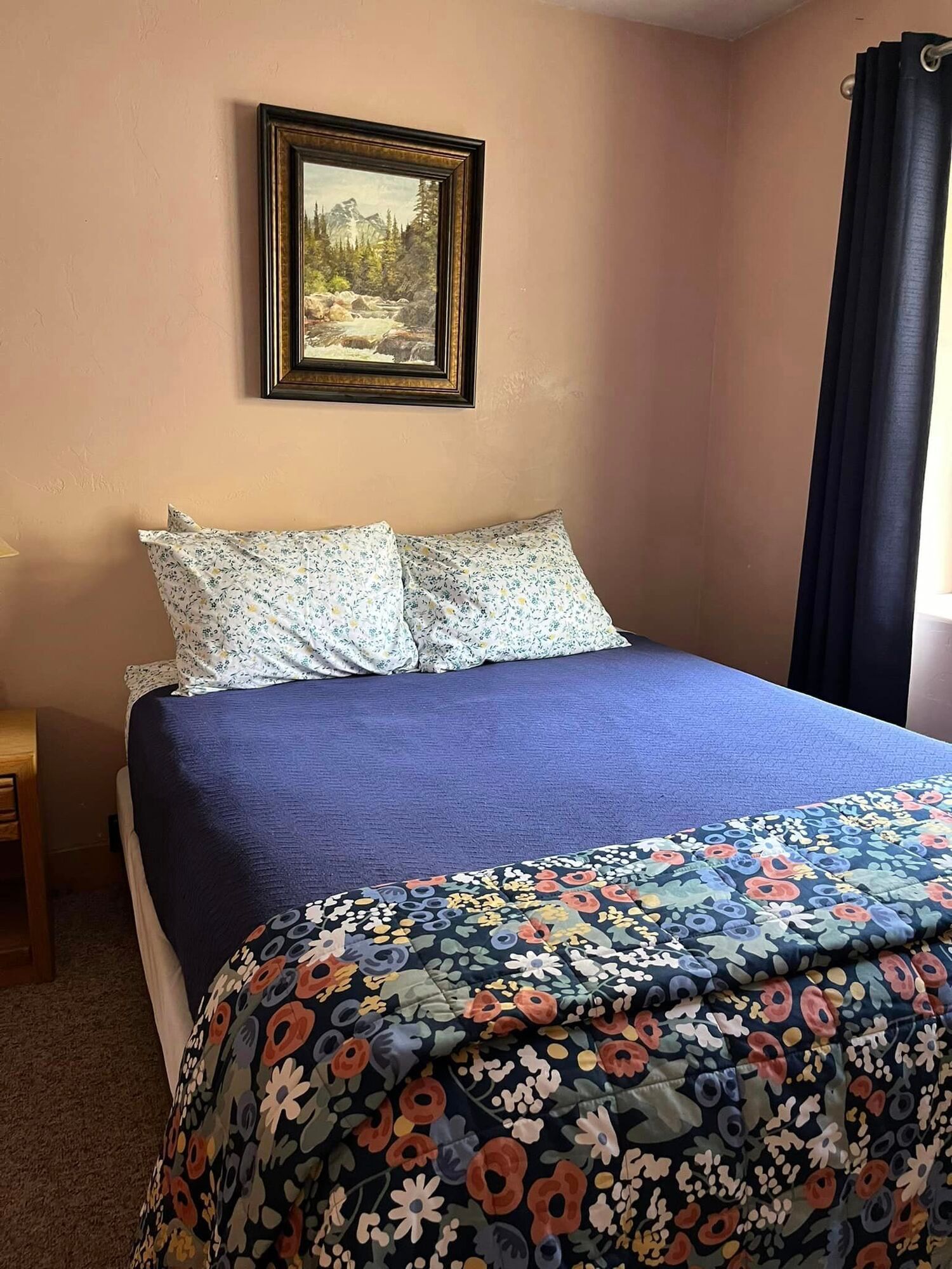 A bedroom with a bed , a painting on the wall , and a window.