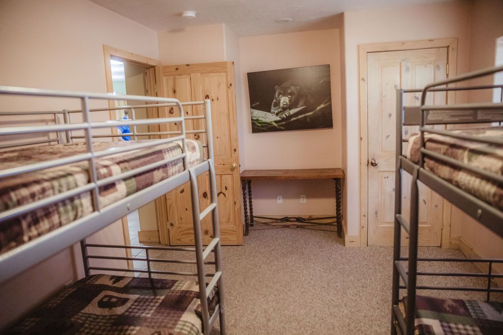 A bunk bed room with four bunk beds and a desk.