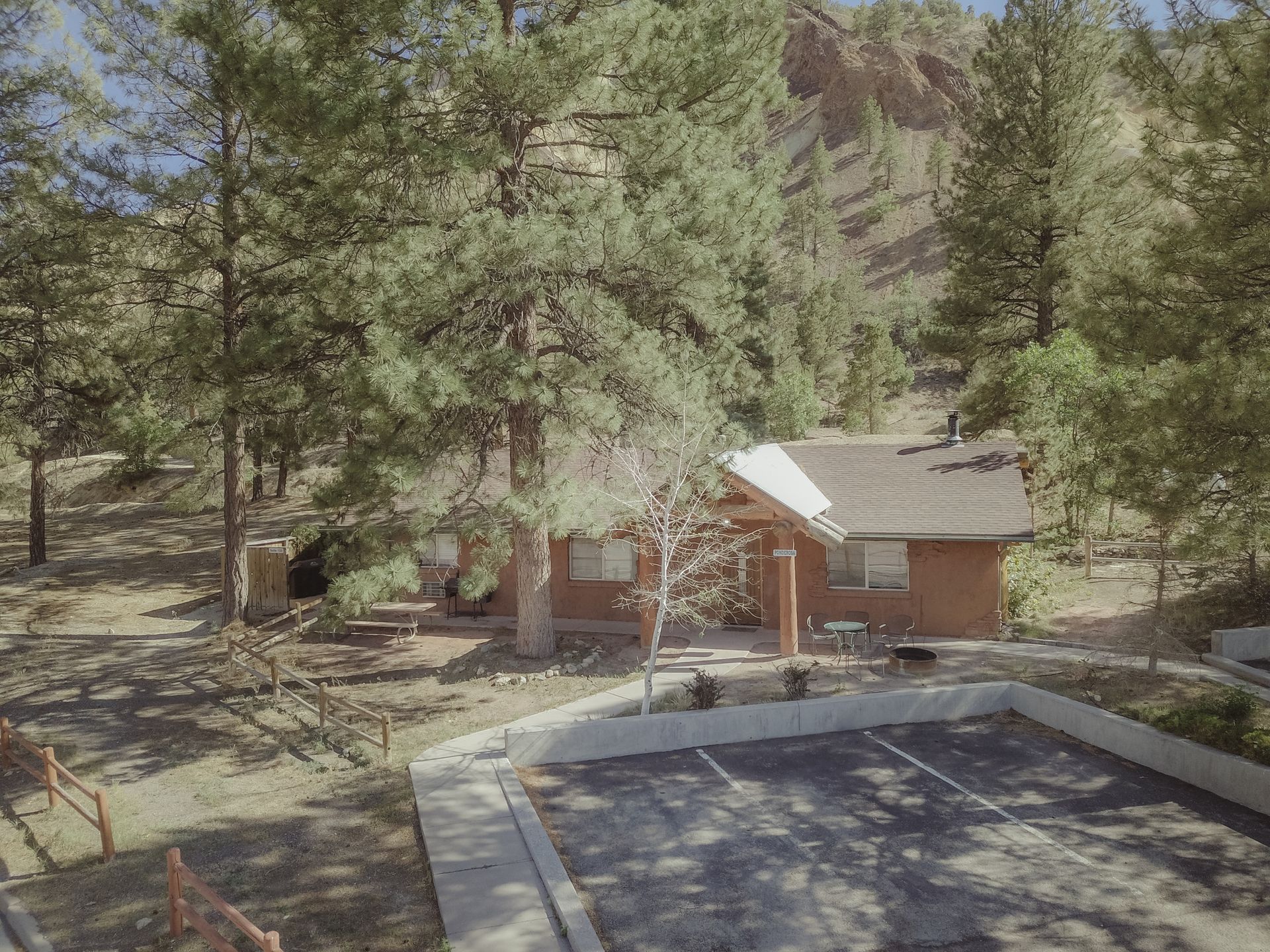 An aerial view of a small house in the middle of a forest.