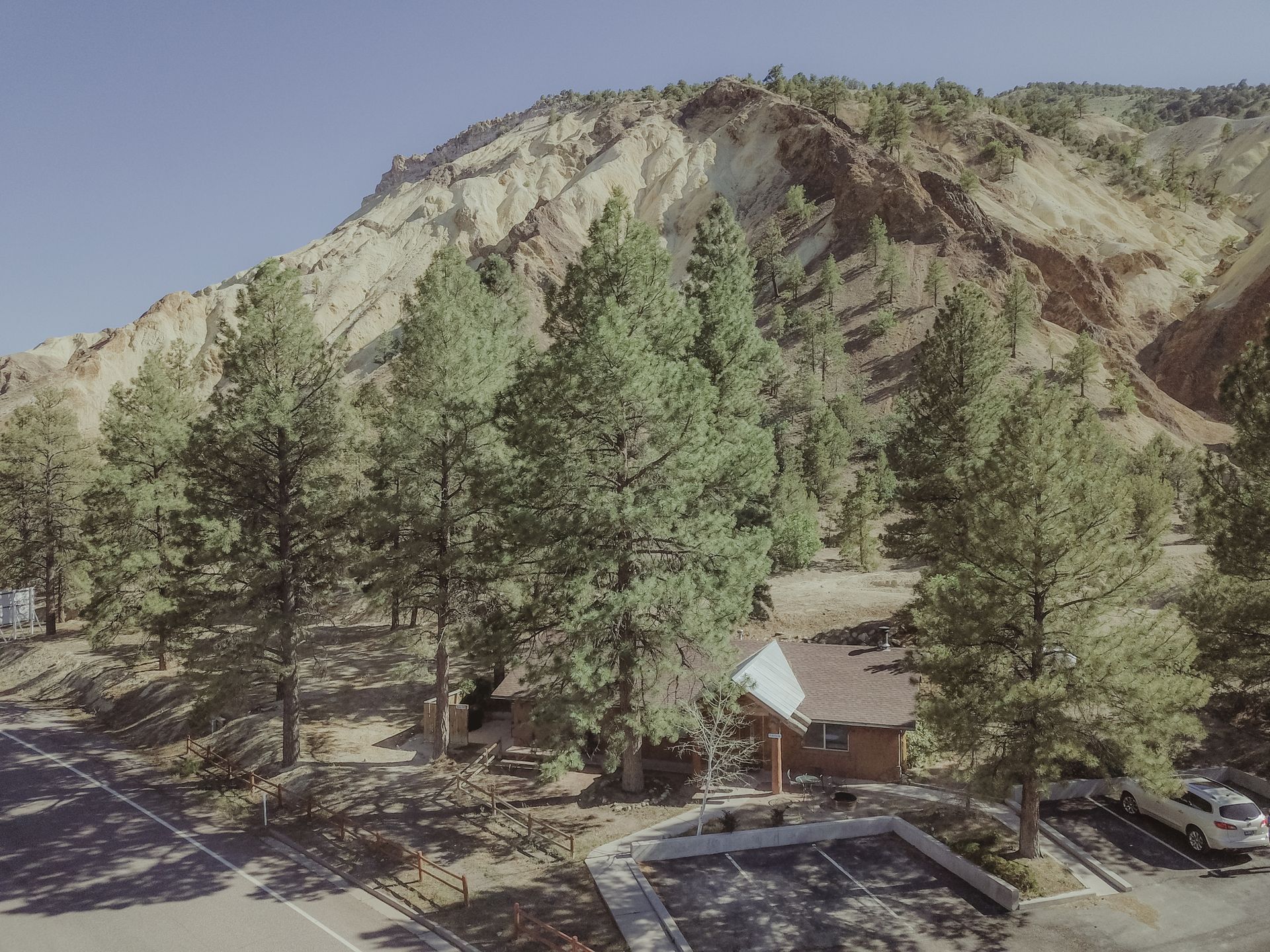 An aerial view of a parking lot in front of a mountain covered in trees.