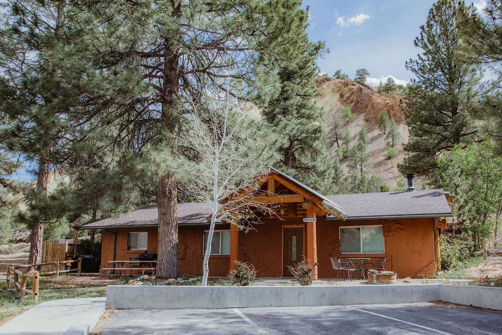 A house is surrounded by trees and has a parking lot in front of it.