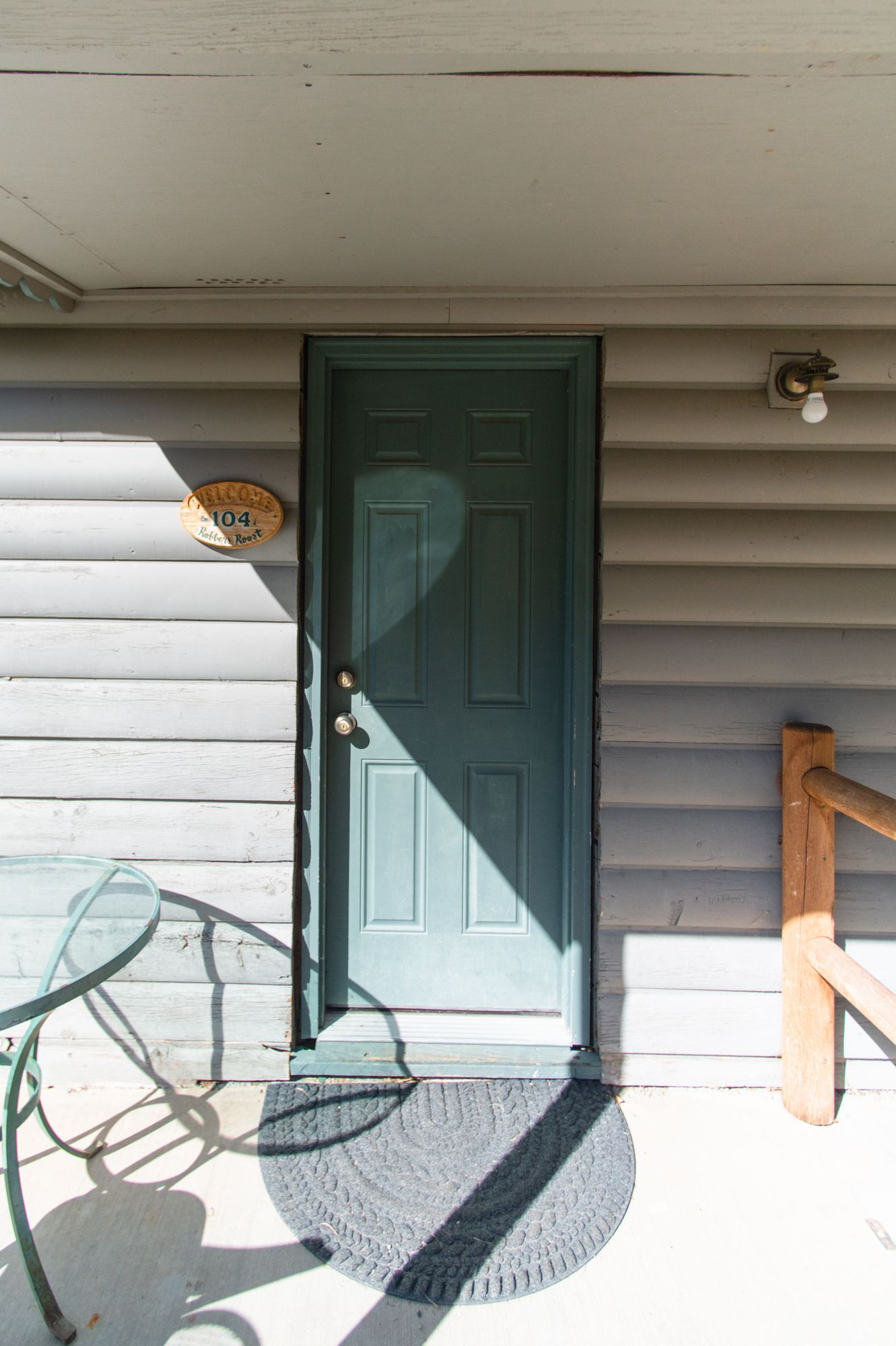 A blue door is sitting on a porch next to a table and chairs.