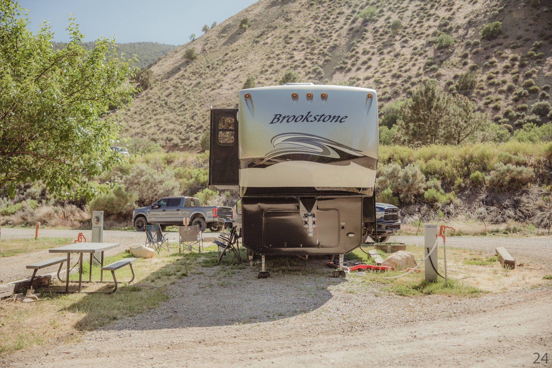 A rv is parked in a gravel lot next to a picnic table.