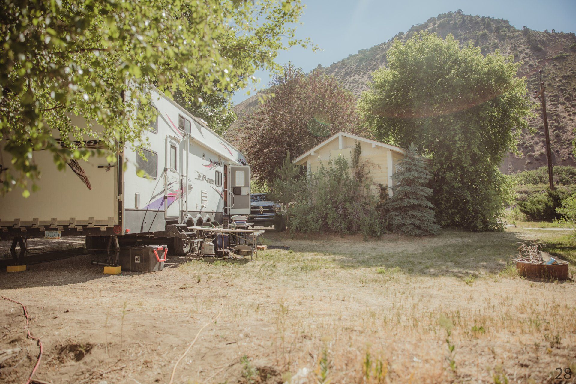 A rv is parked in a field next to a house.