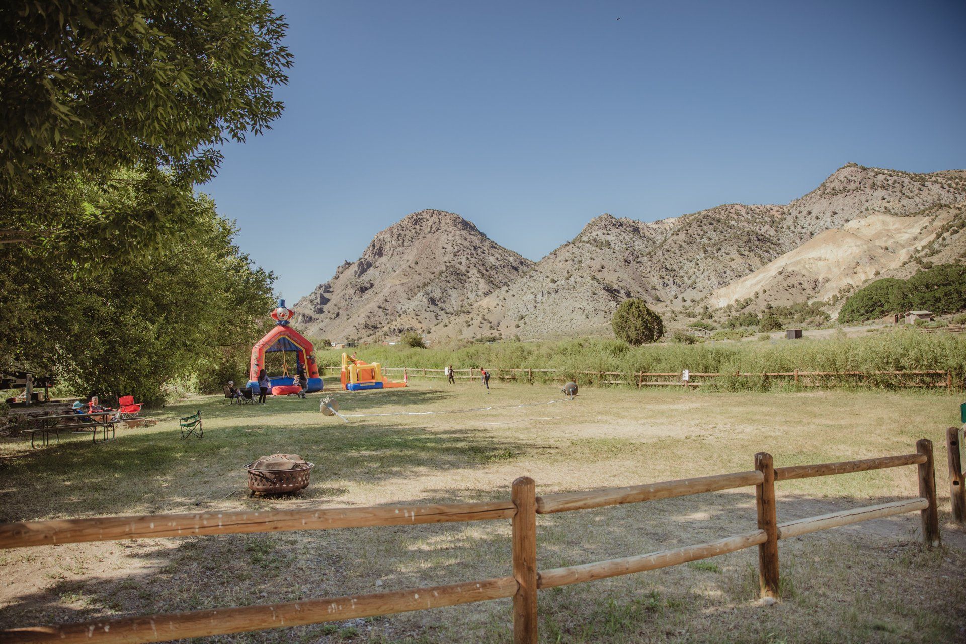 there is a bouncy house in the middle of a field with mountains in the background .