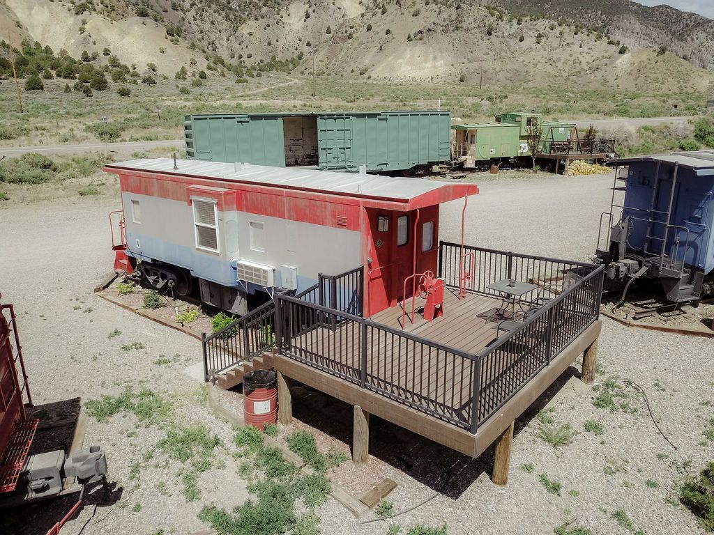 A red , white and blue train car with a deck in front of it.