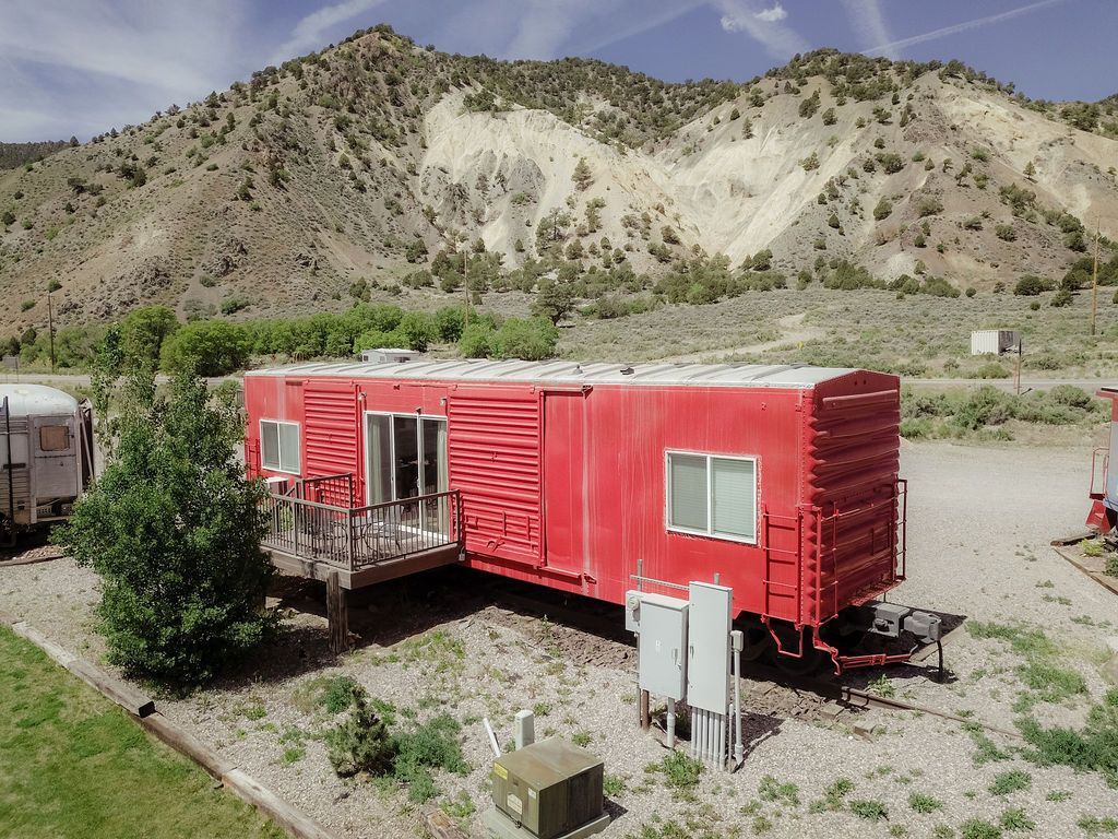 A red trailer is parked in front of a mountain.