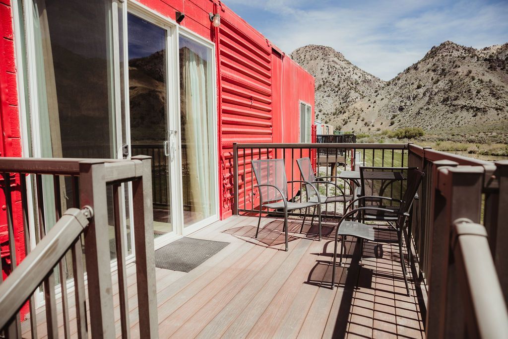 A red house with a wooden deck and a mountain in the background.