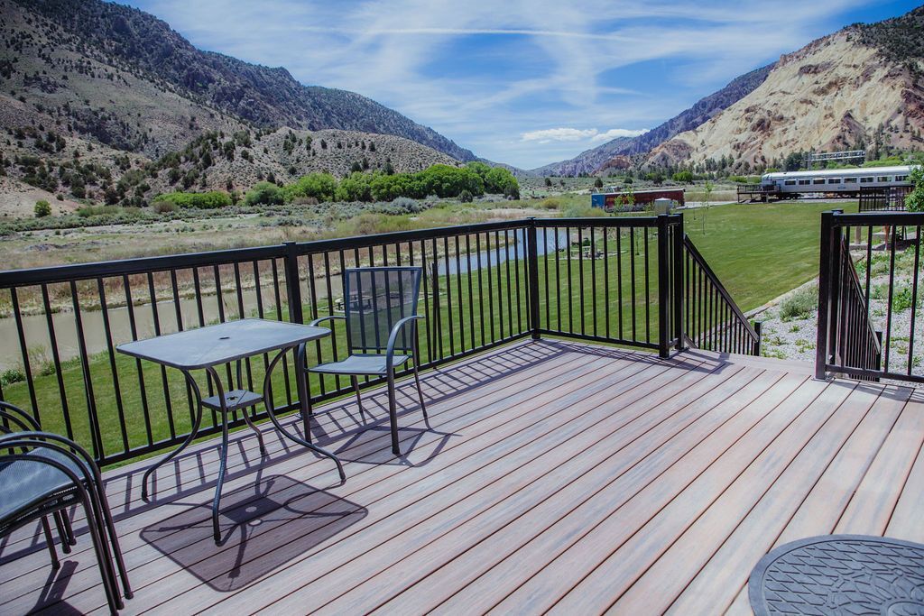 There is a table and chairs on the deck with a view of the mountains.