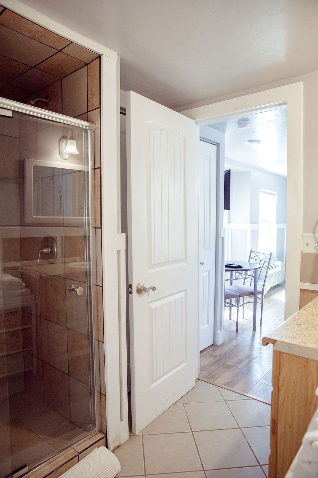 A bathroom with a walk in shower , sink and mirror.