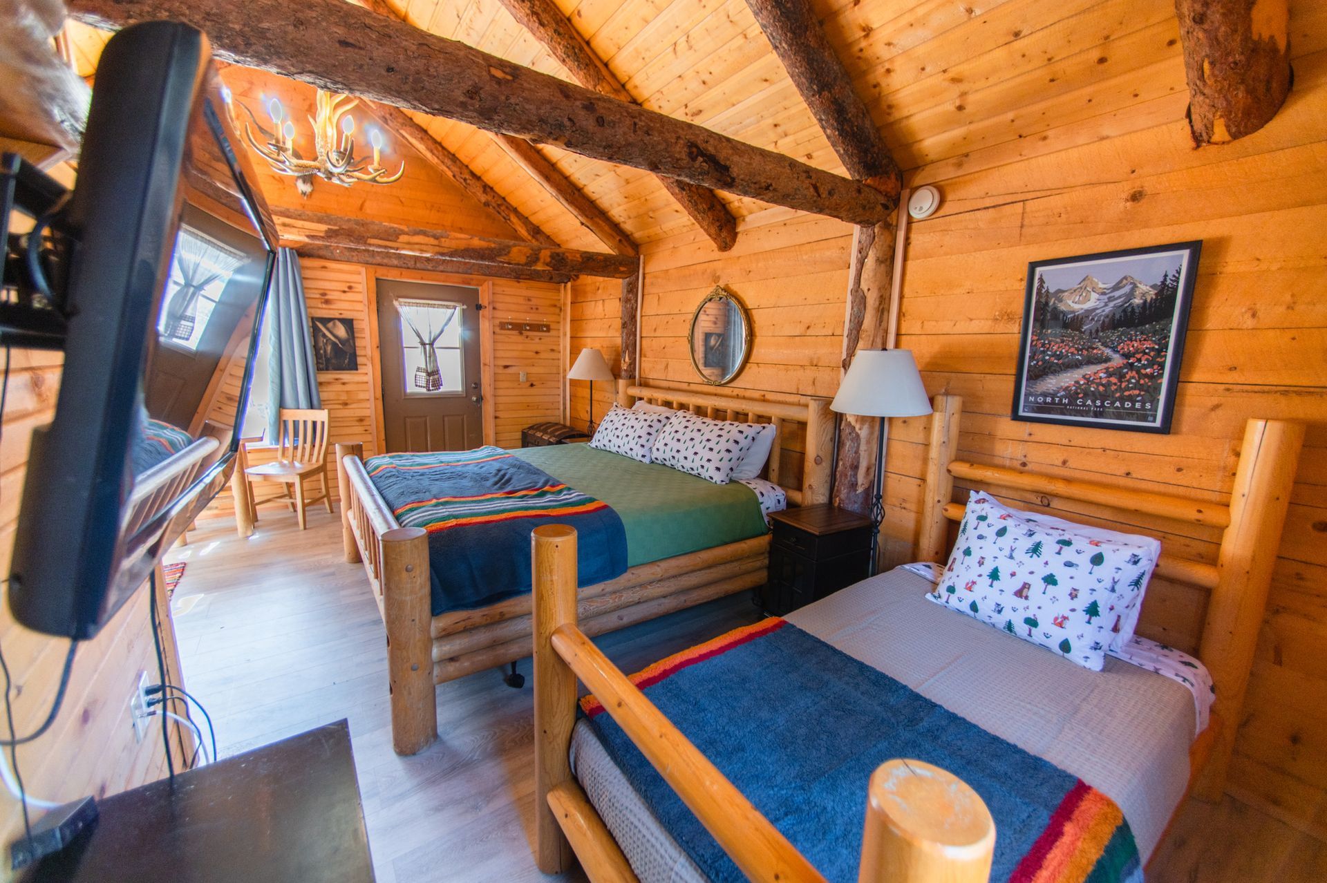 A bedroom in a log cabin with two beds and a television.