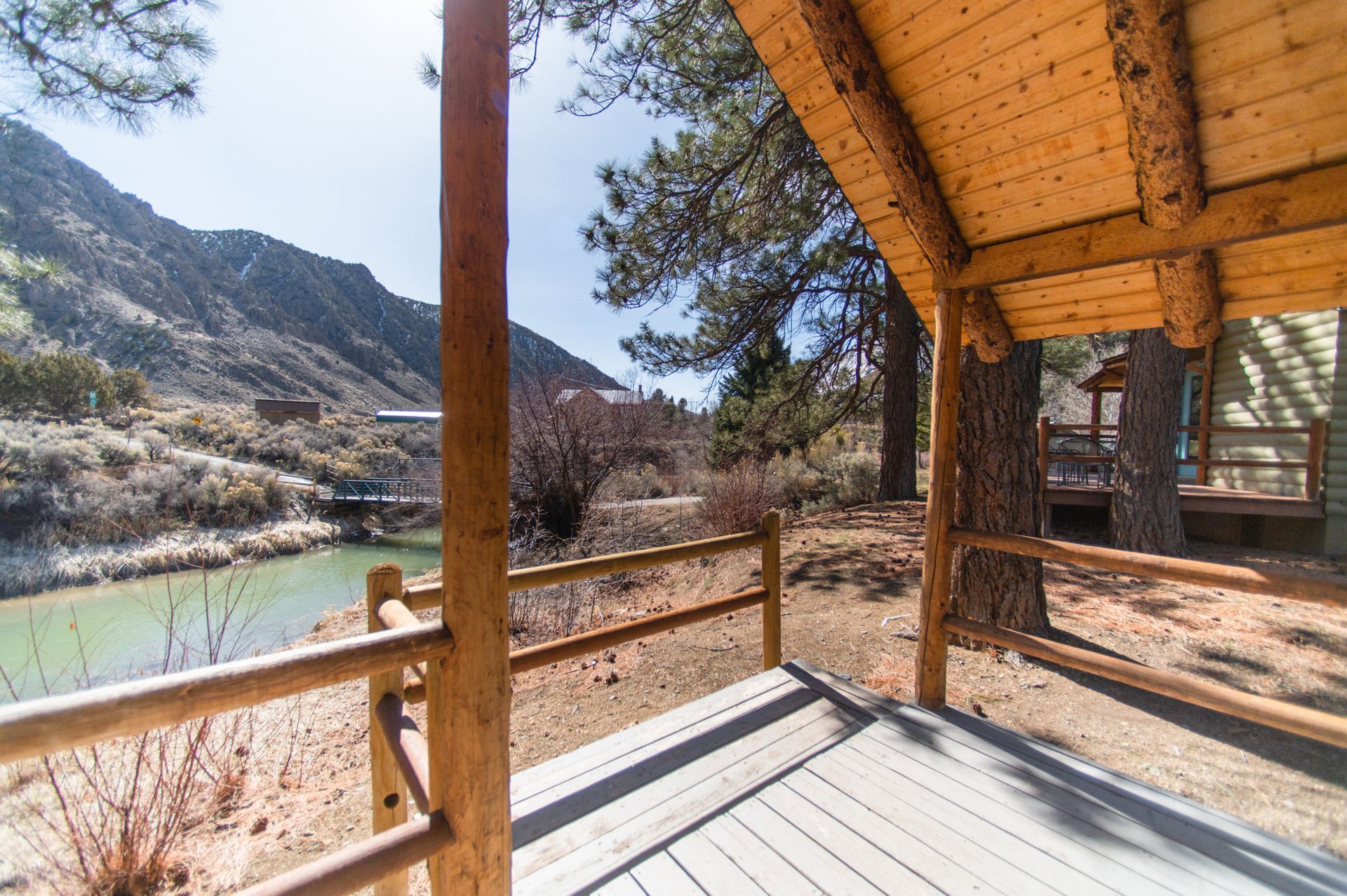 A wooden deck with a view of a river and mountains.