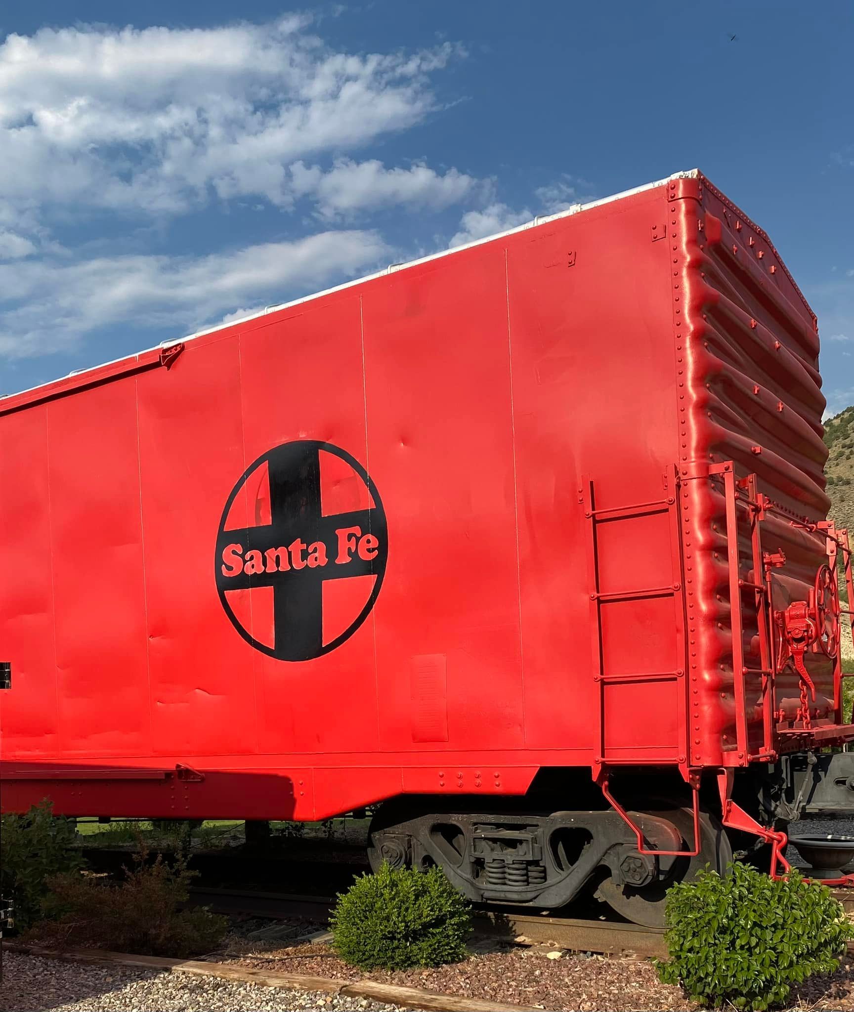 A red santa fe train car is parked in the dirt