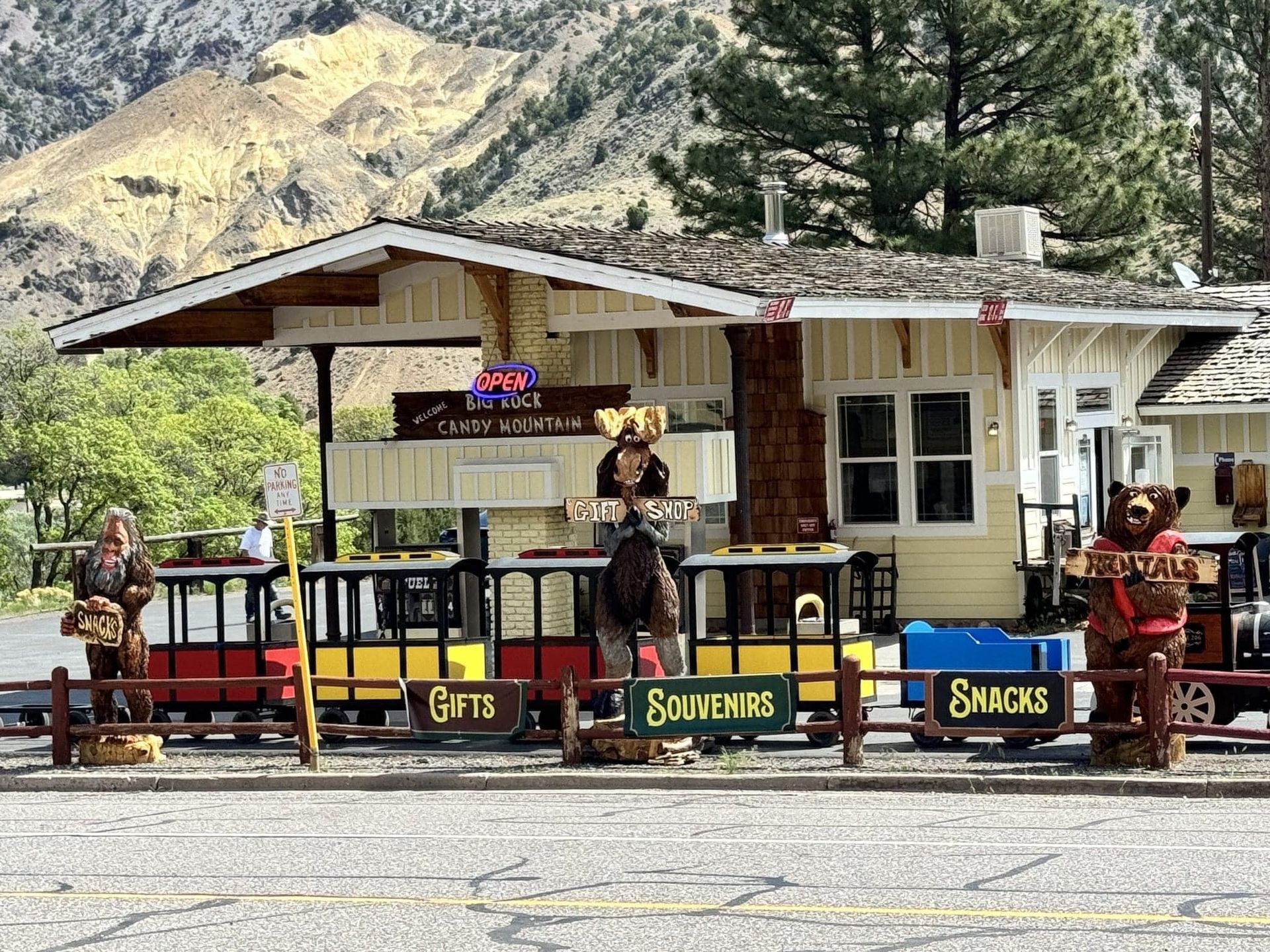 A small train is parked in front of a building with a sign that says souvenirs.