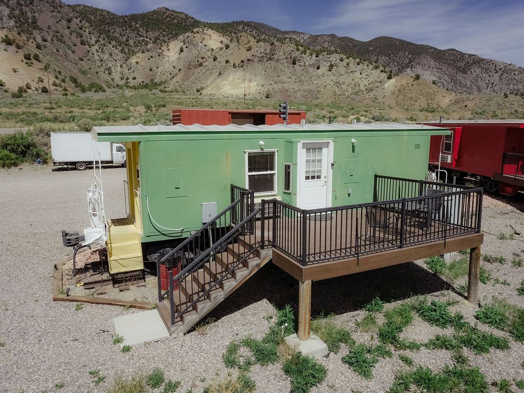 A green trailer with a deck and stairs in front of it.