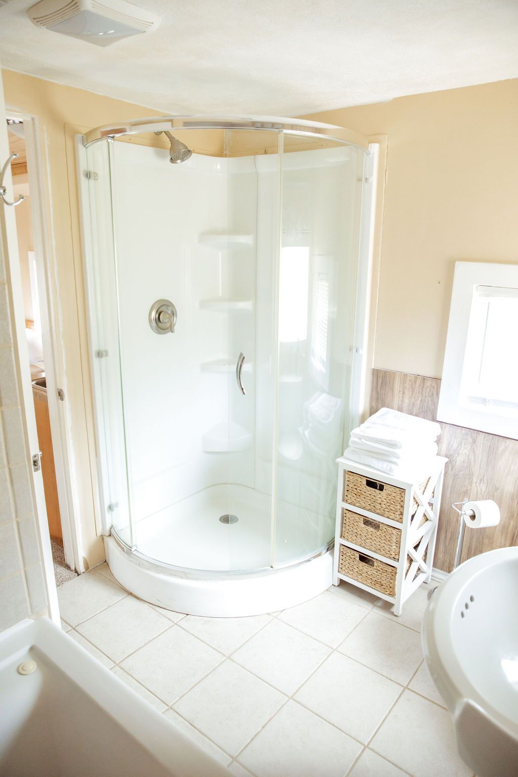 A bathroom with a tub , shower , and wicker baskets.